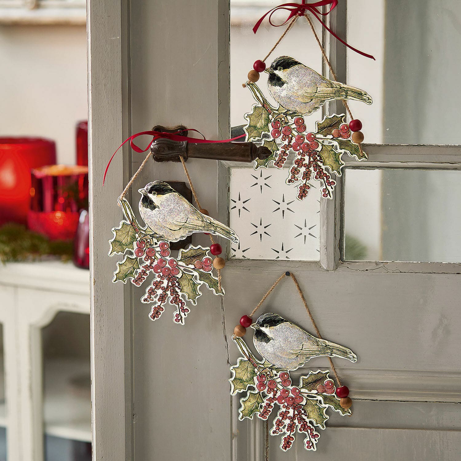 Kerstdecoraties met vogels en rode bessen aan een grijze deur, feestelijke ornamenten