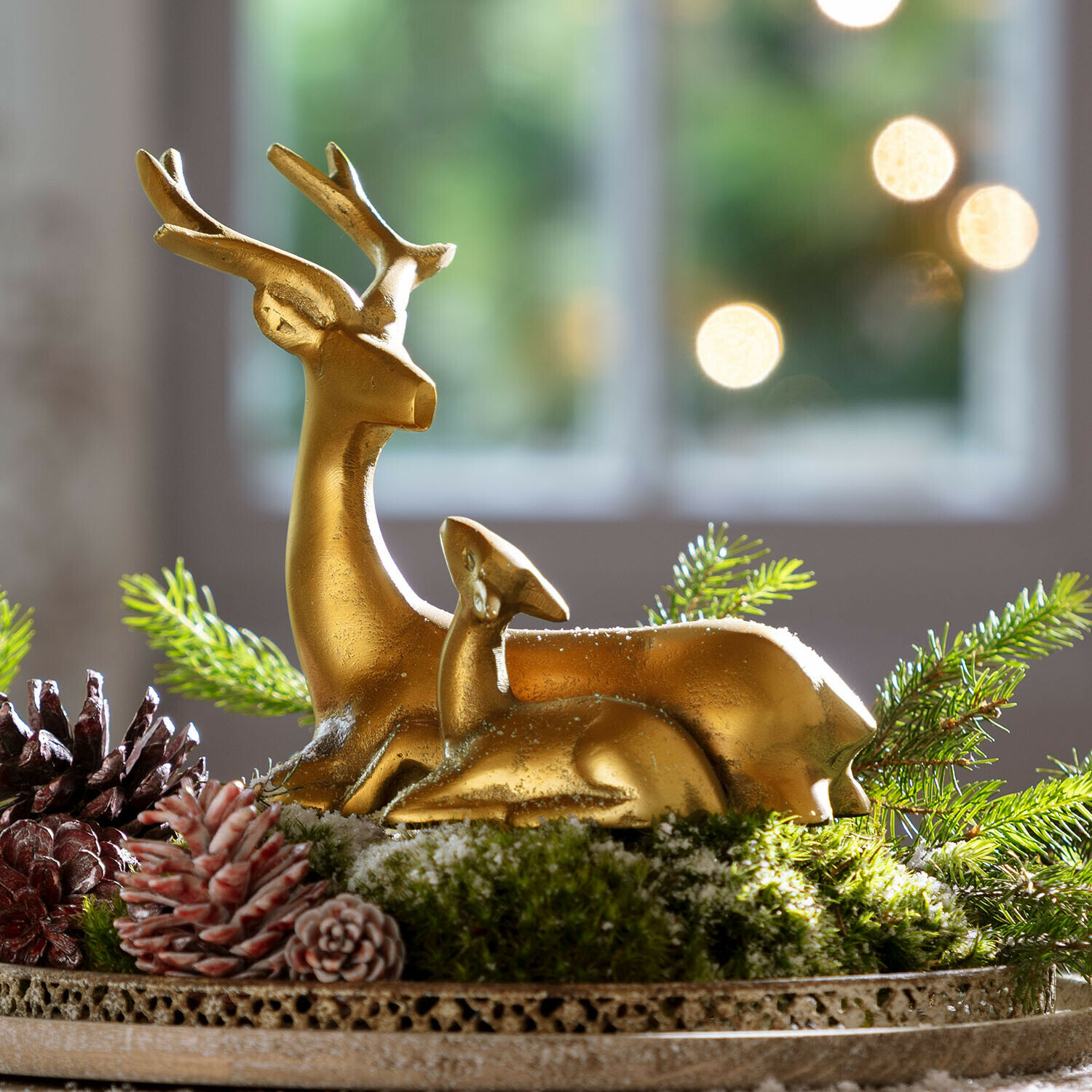 Gouden hertenfiguren op groen mos met dennenappels, natuurlijke kerstdecoratie