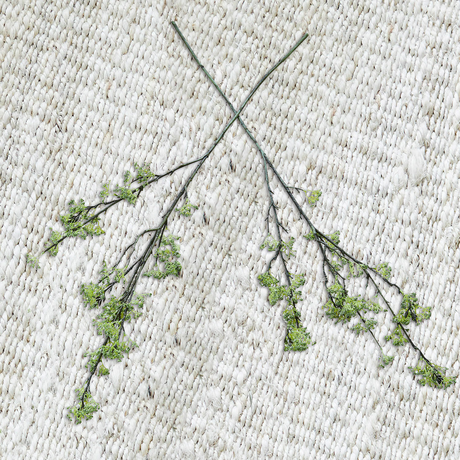 Sierbloem set van 2 Mormant Twee dunne takken met groene bladeren op een lichte, grof geweven decoratieve vloerkleed