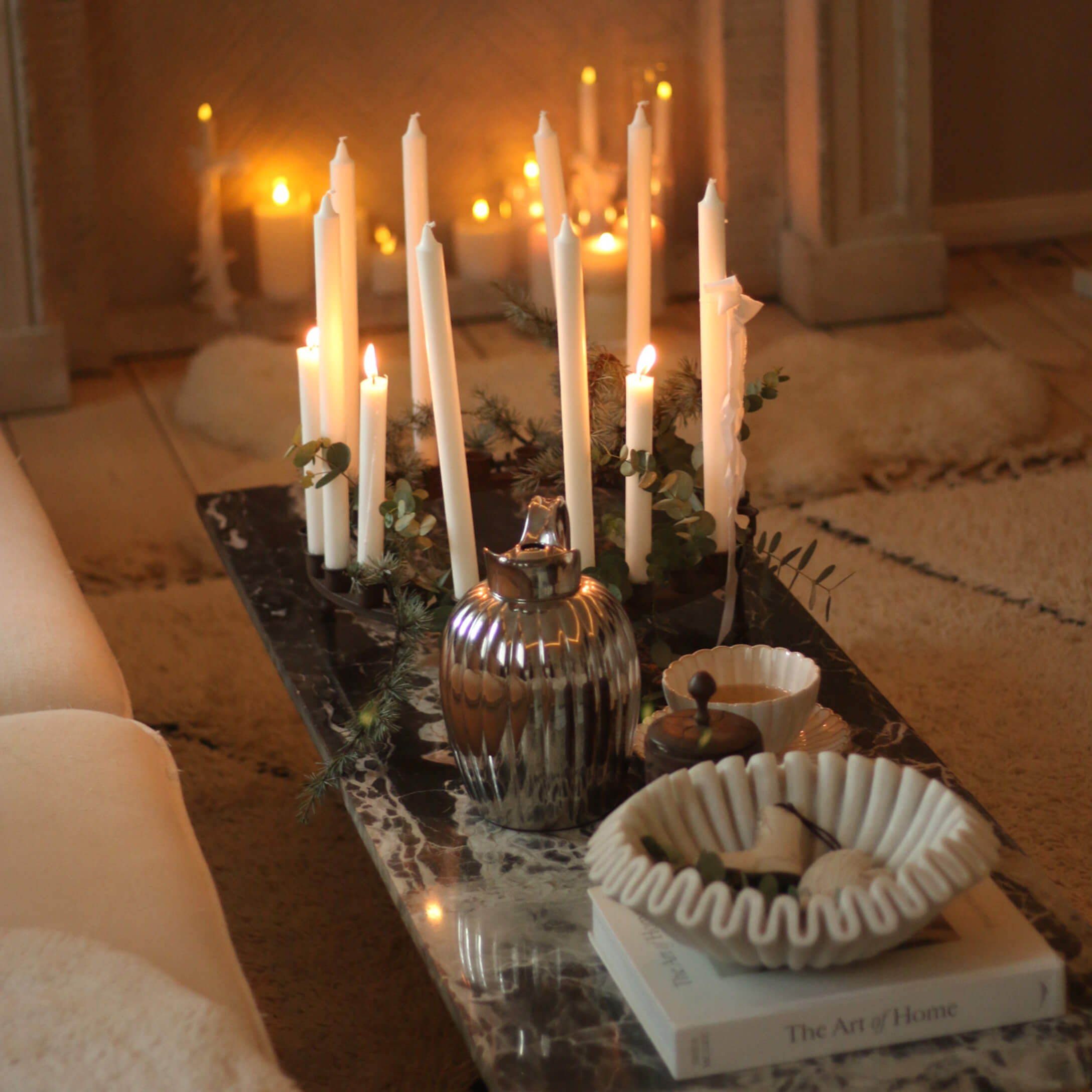 Decoratieve kandelaar met witte kaarsen op marmeren tafel met keramische schaal en metalen kan