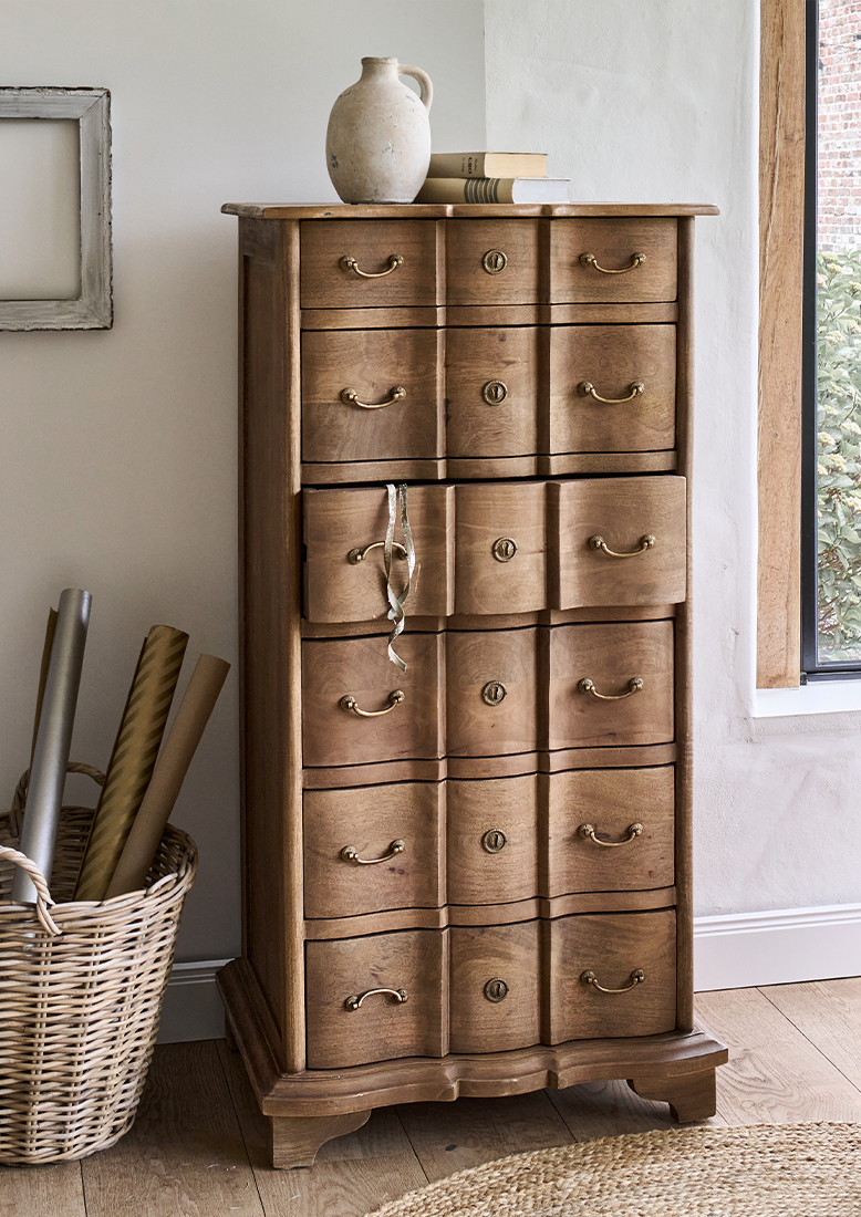 Houten ladekast met zes laden en messing handgrepen in natuurlijke houtkleur in lichte kamer