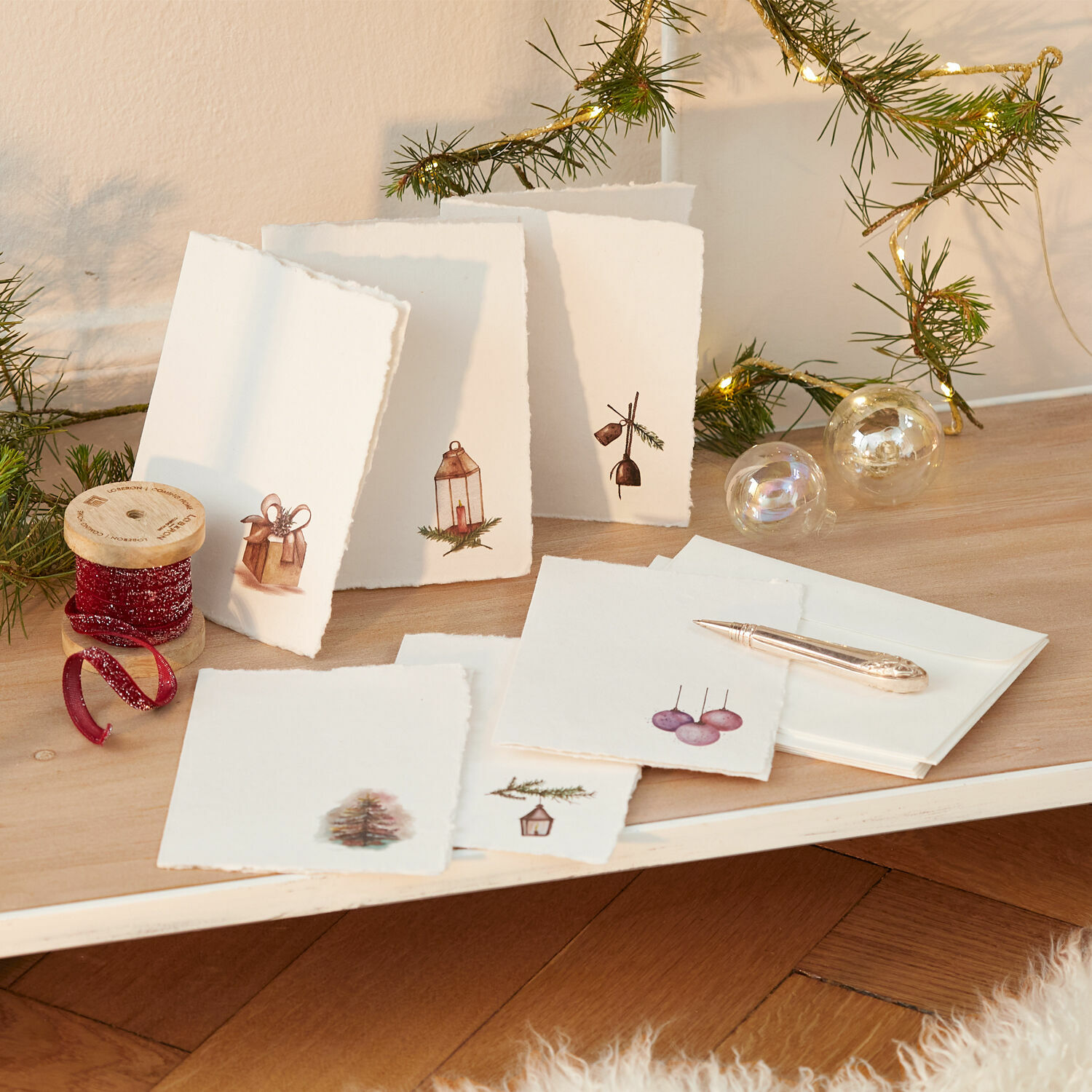 Wenskaart set van 6 Aeloria Set handgemaakte kerstkaarten van papier met feestelijke motieven en rode decoratieve lint op houten tafel