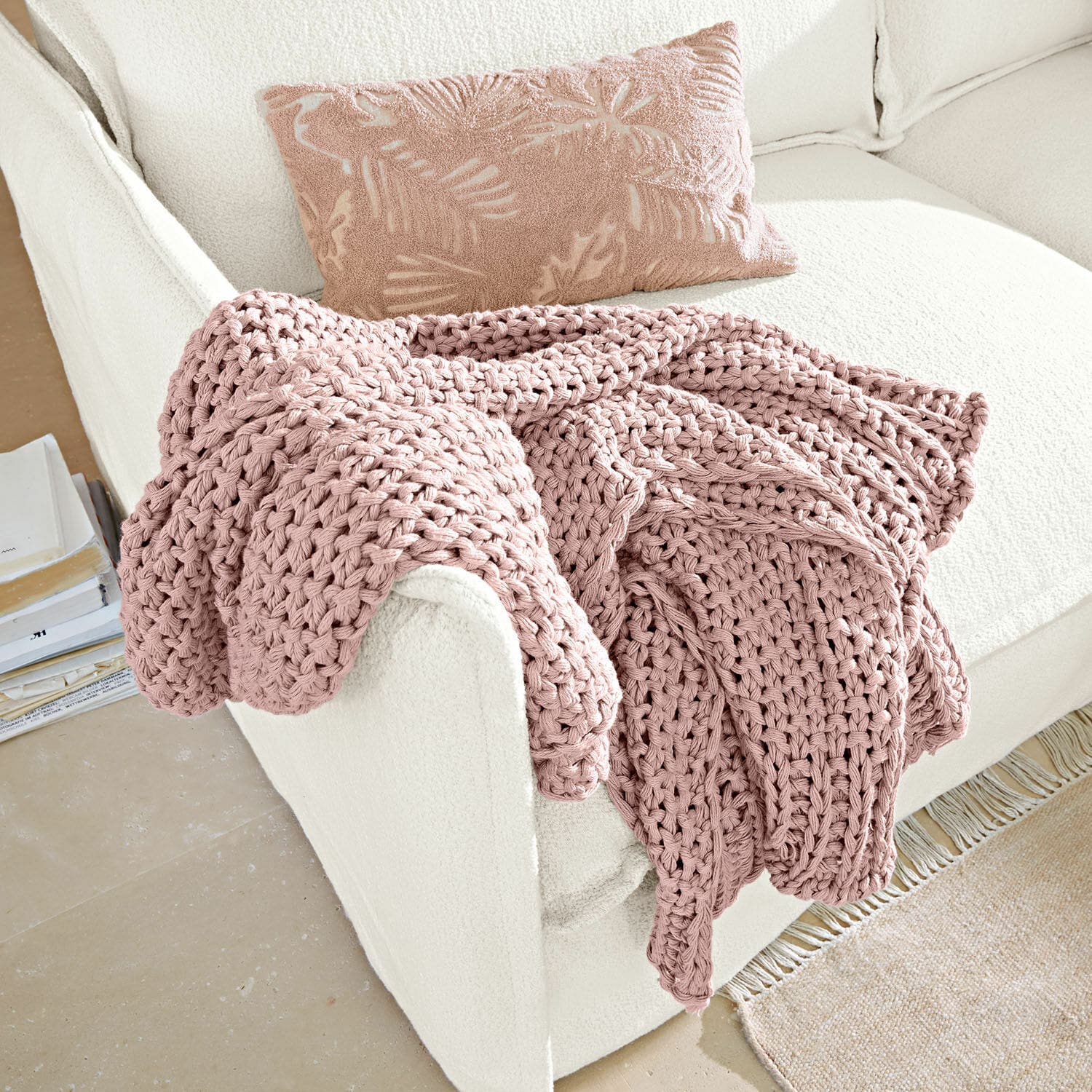 Plaid Plixoren Roze grof gebreide deken op witte bank met decoratief kussen met bladmotief, zacht en knus