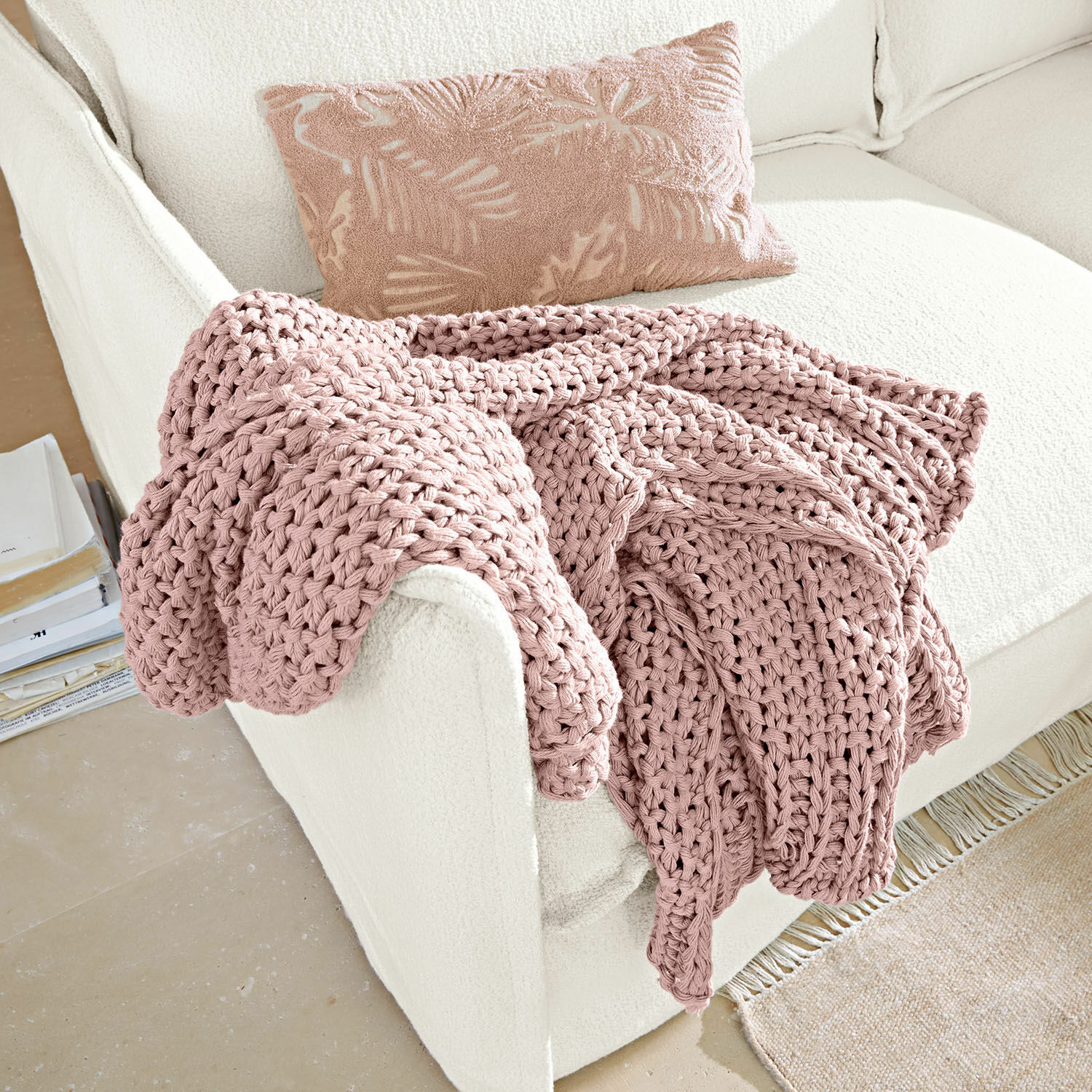 Plaid Plixoren Roze grof gebreide deken op witte bank met decoratief kussen met bladmotief, zacht en knus