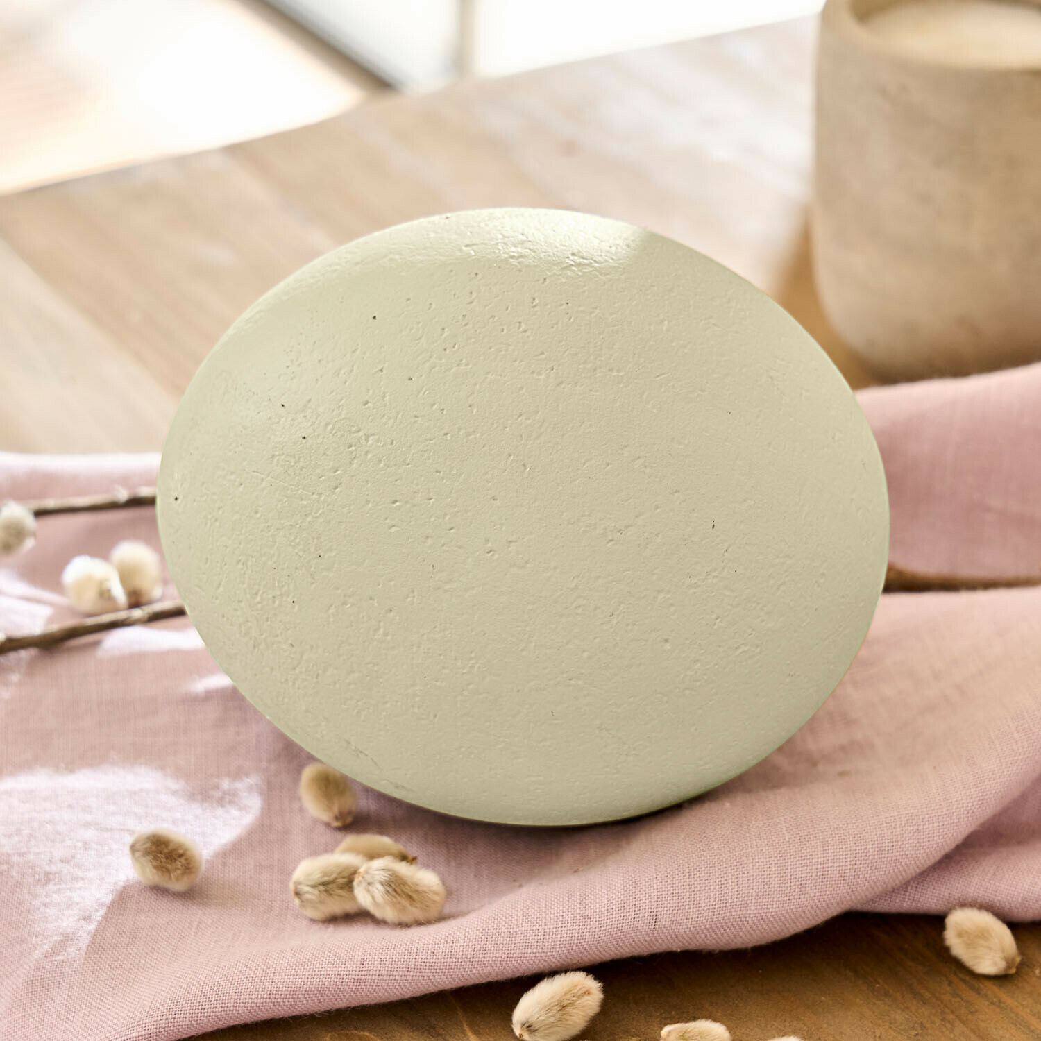 Decoratief ei van matte keramiek in crèmekleur op roze stof voor woondecoratie