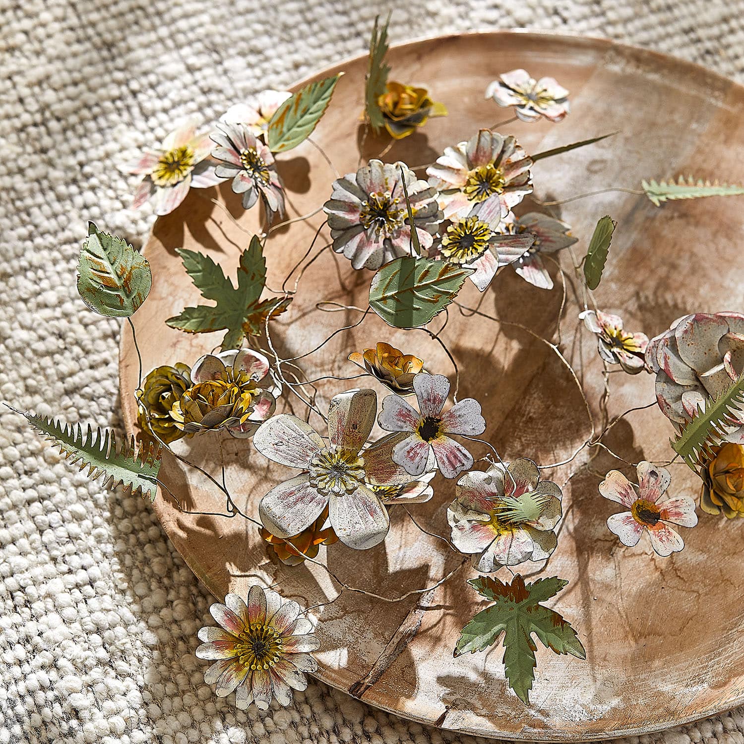 Decoratieve metalen bloemen en bladeren in pasteltinten op een houten schaal, interieurdecoratie
