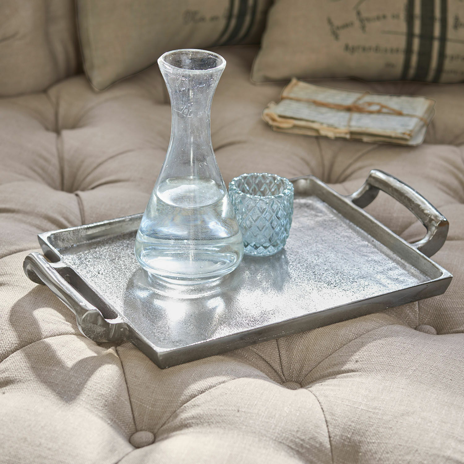 Dienblad Connaire Decoratief zilverkleurig metalen dienblad op beige gewatteerde stof met karaf en glas