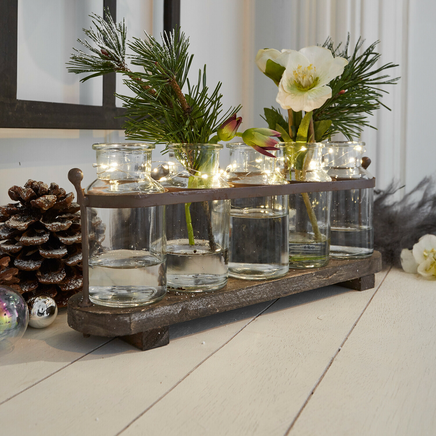 Decoratieve set glazen vazen op houten plank met groene takken en LED-lichtjes voor woondecoratie
