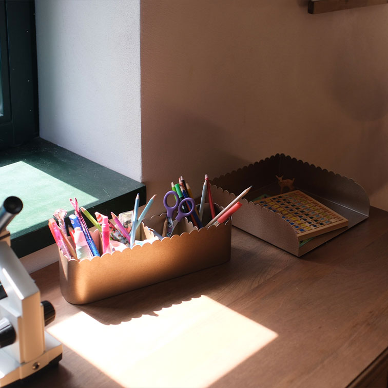 Bruine metalen bureau-organizers met golvende randen, gevuld met schrijfwaren en een boek