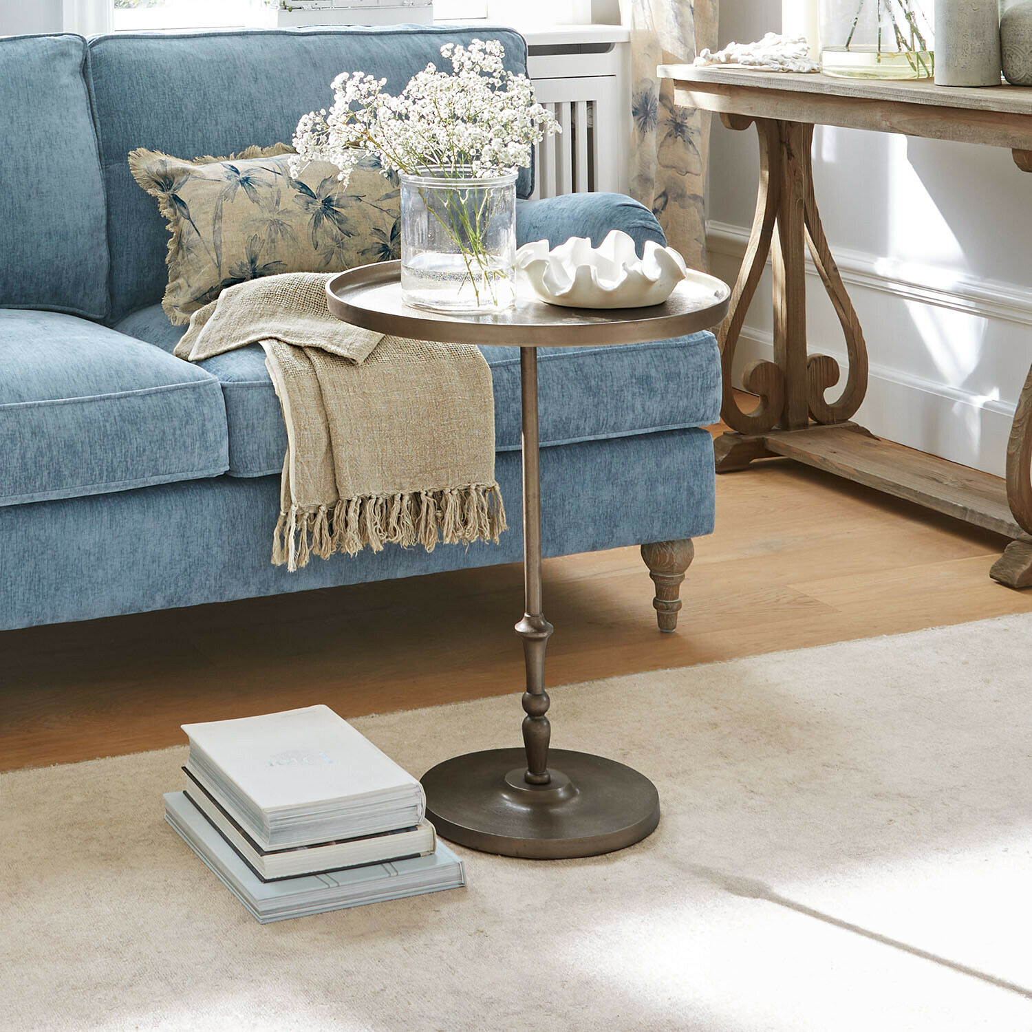 Ronde metalen bijzettafel in woonkamer met blauwe bank en decoratief kleed