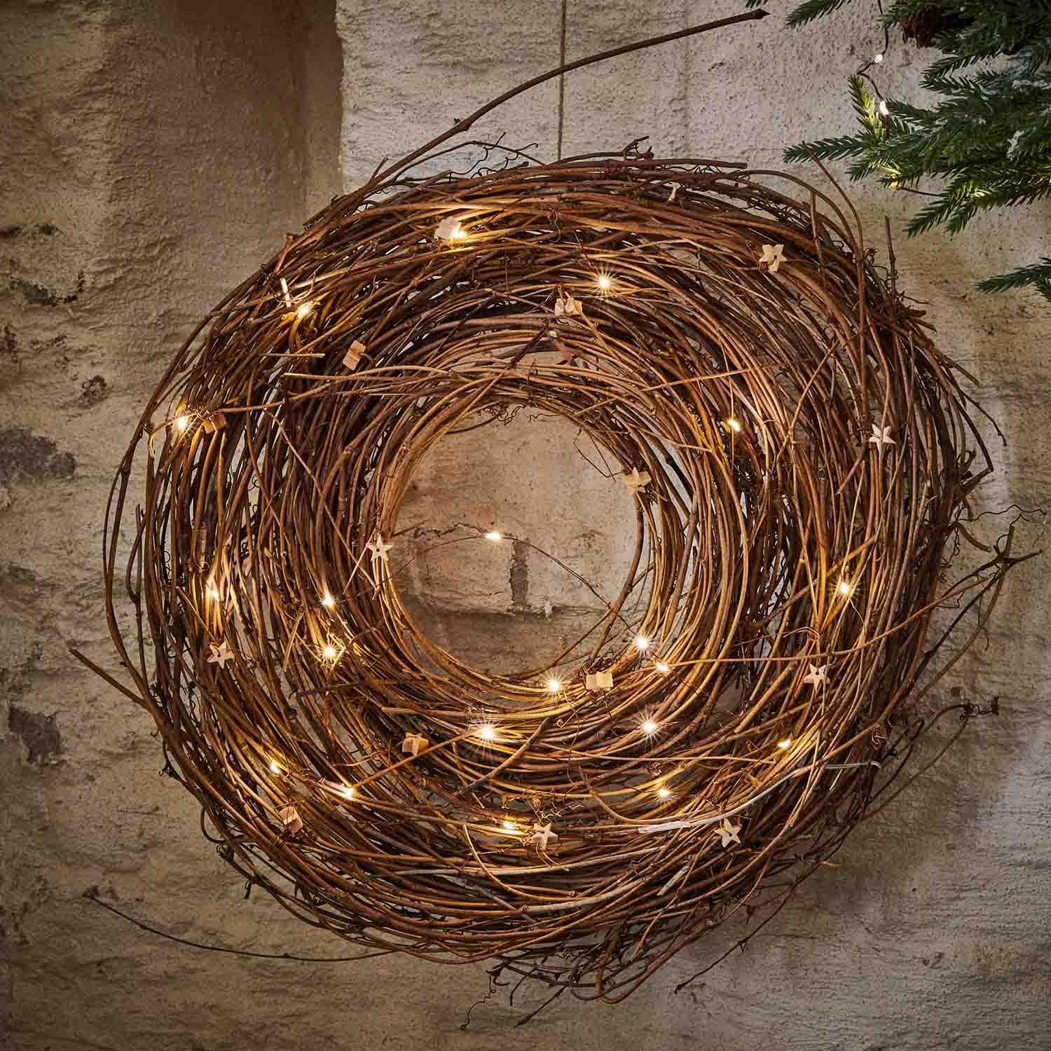 Decoratieve krans van natuurlijke takken met subtiele LED-verlichting aan de muur