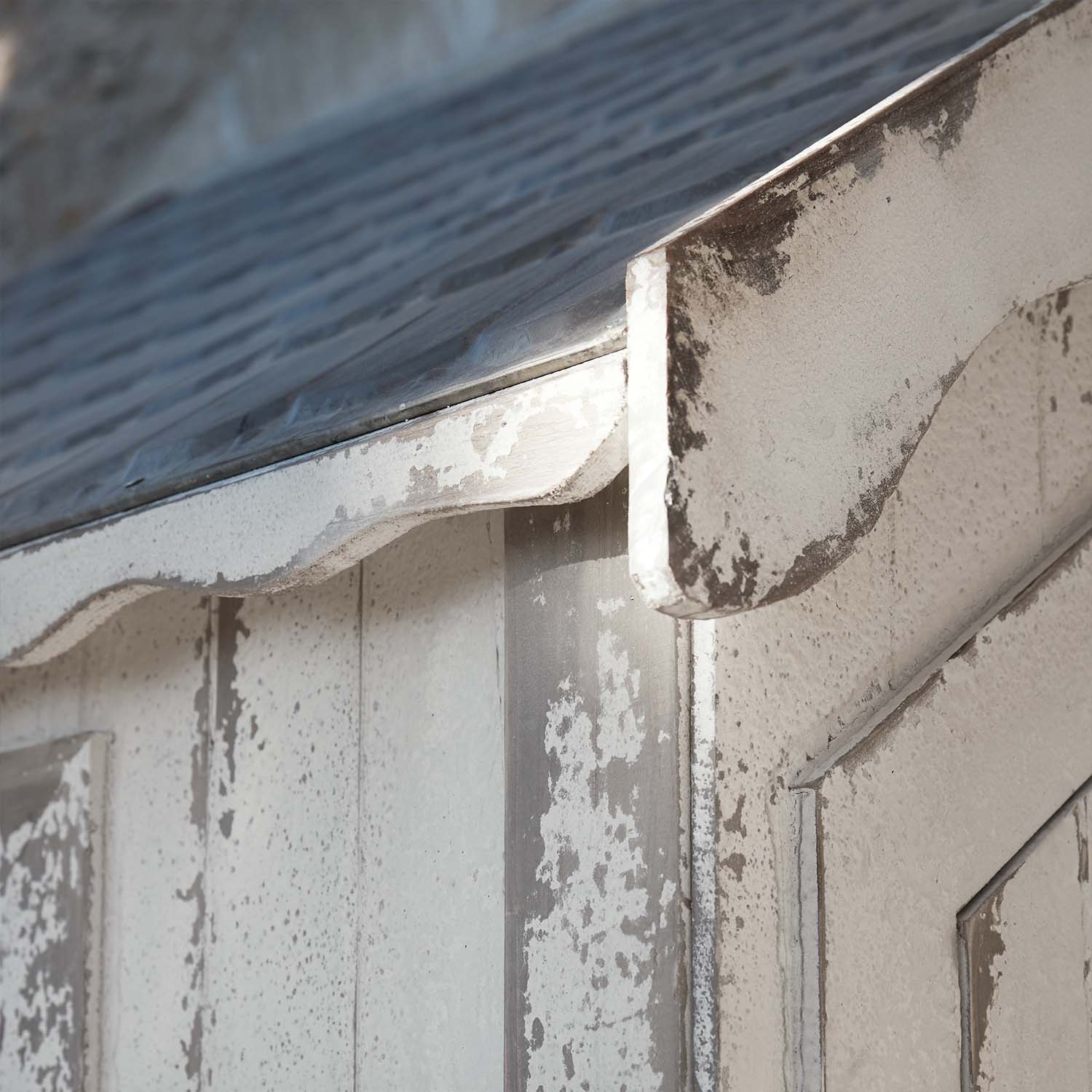 Close-up van verweerde witte houten constructie met metalen dak en gebogen rand