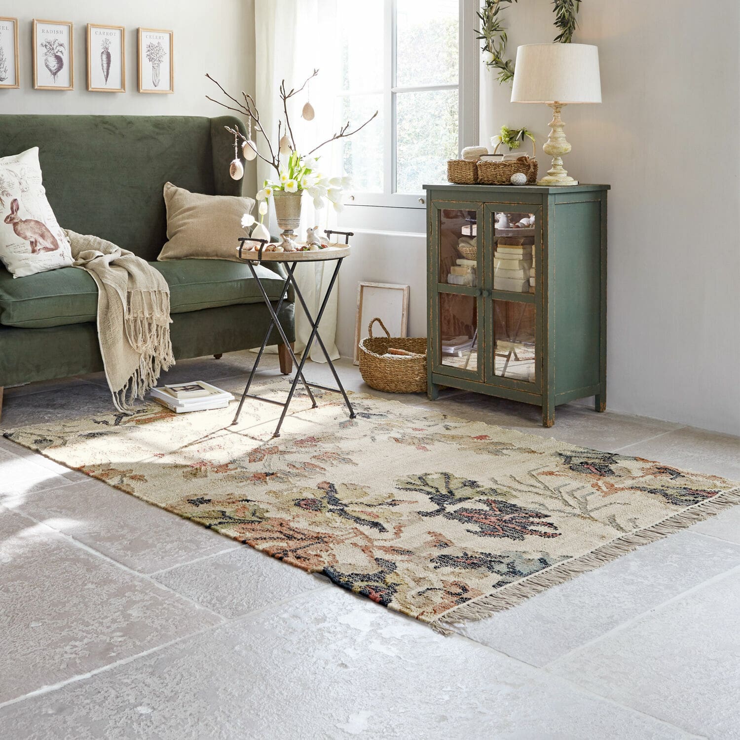 Gezellige woonkamer met groene bank, houten kast en bloemenpatroon vloerkleed op lichte vloer