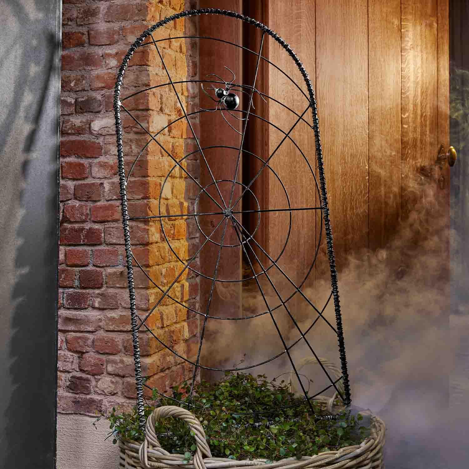 Zwarte metalen spinnenwebdecoratie met spin voor een bakstenen muur en houten deur