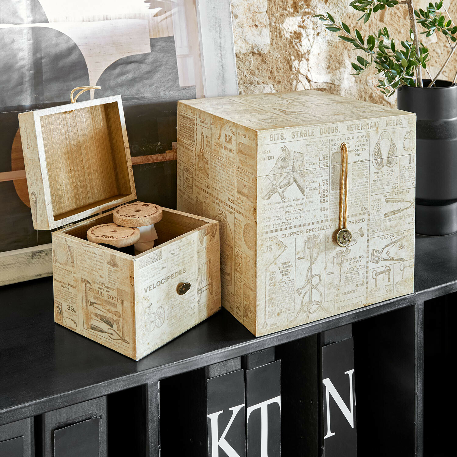 Decoratieve houten dozen in beige met vintage print op zwarte plank voor opbergruimte