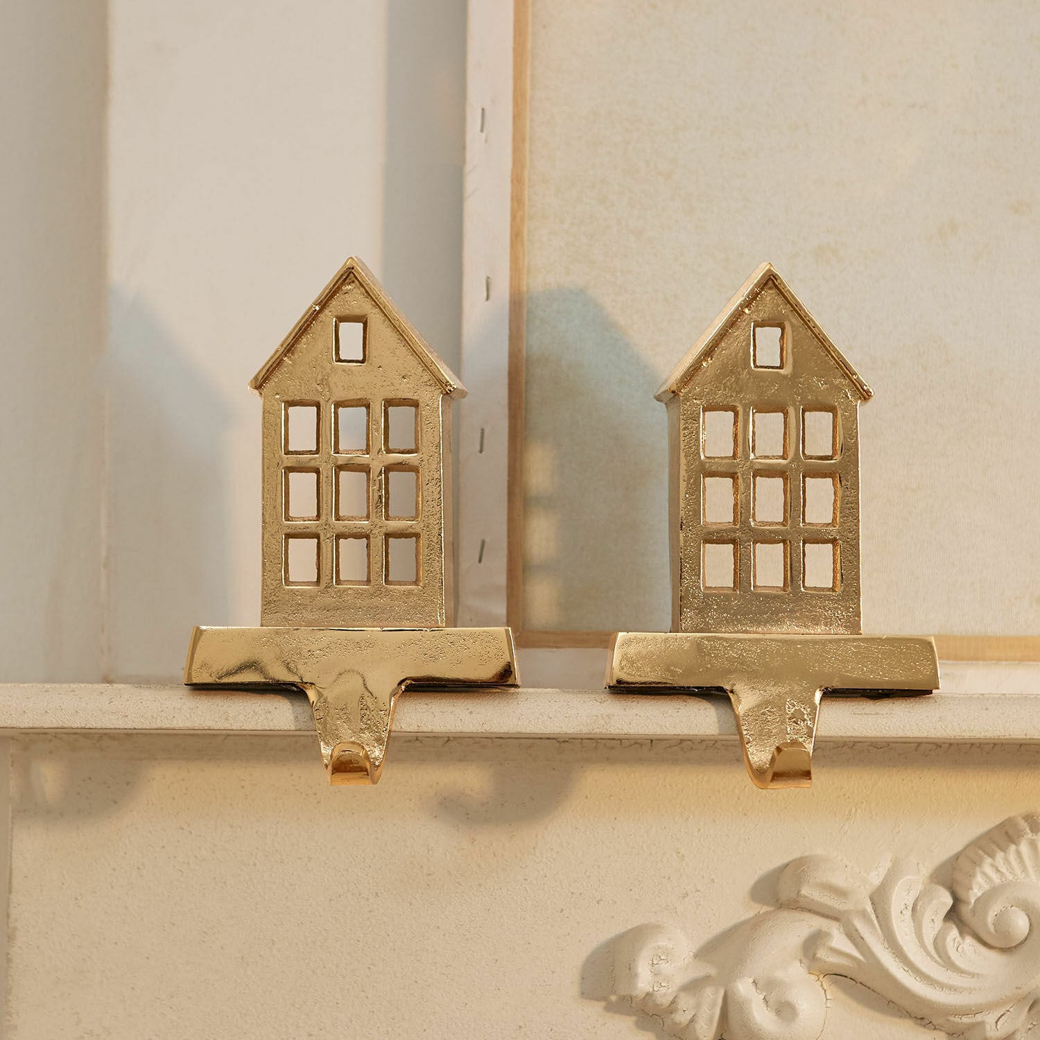 Gouden metalen huisvormige decoraties met haken om versieringen aan de open haard te hangen