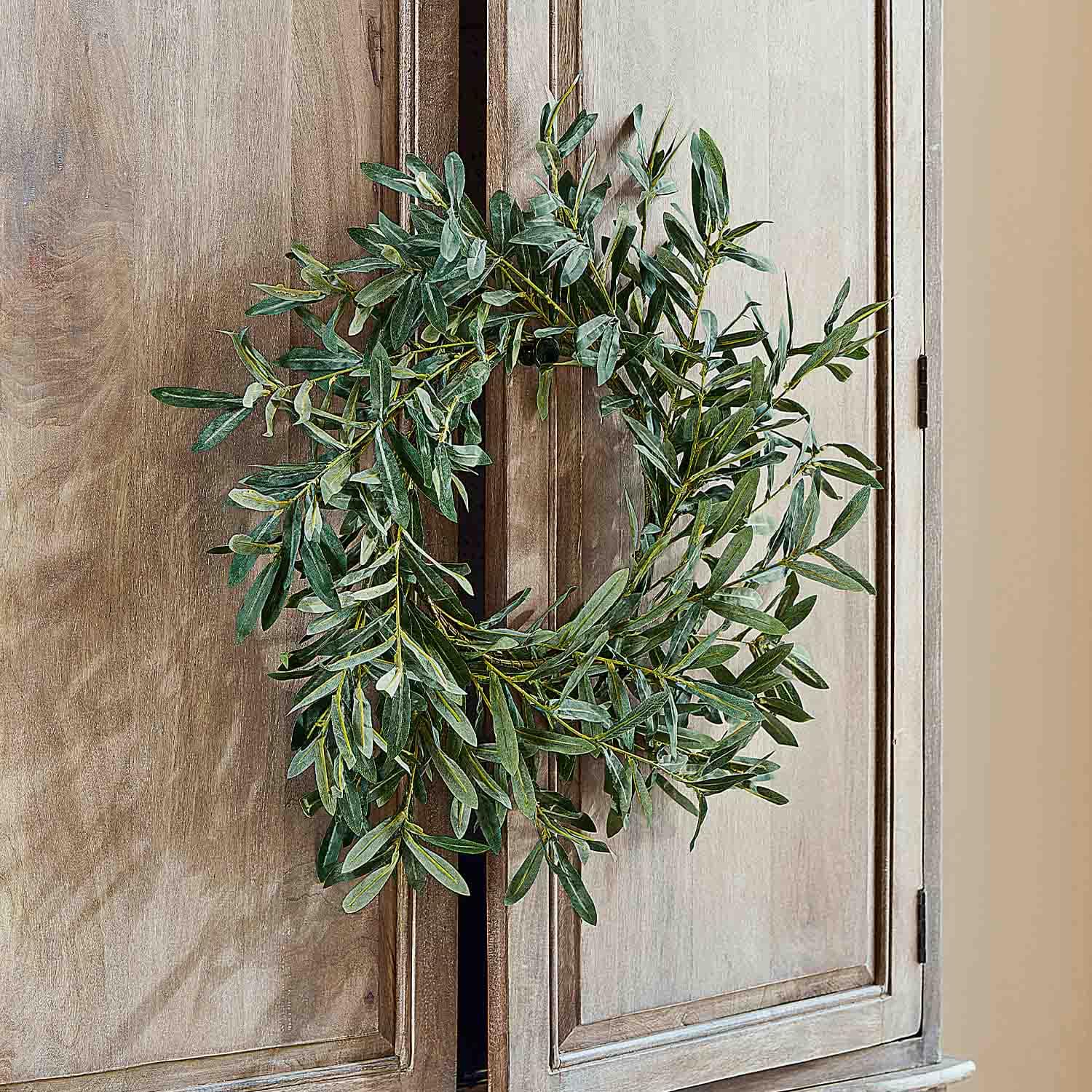 Decoratieve krans van groene bladeren aan houten deur, natuurlijke interieurdecoratie