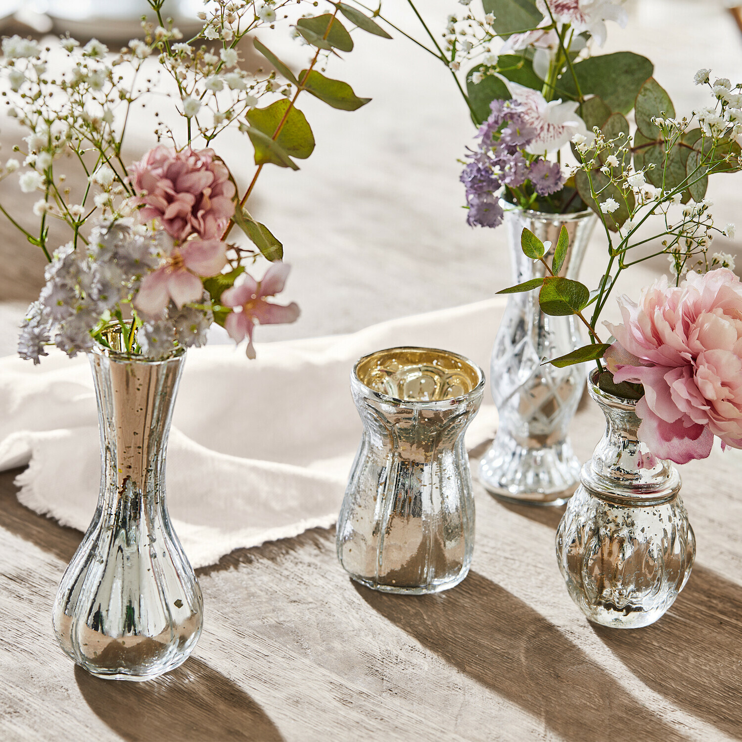 Decoratieve vaas set van 4 Maelie Set van vier zilverkleurige glazen vazen met bloemen op houten tafel, sfeervolle tafeldecoratie
