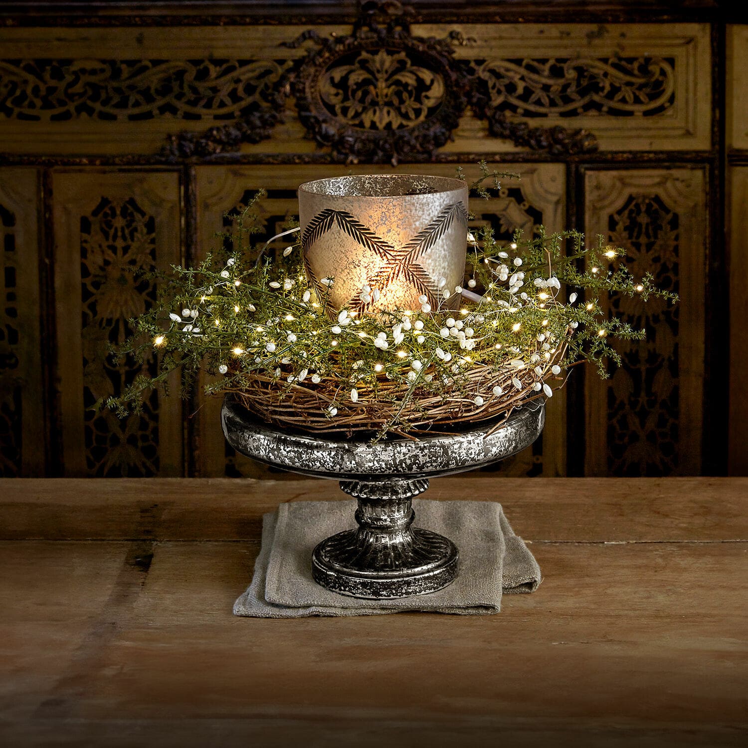Etagère Incantesse Decoratieve zilverkleurige metalen kandelaar met wilgenkrans en LED-lichtjes op houten tafel