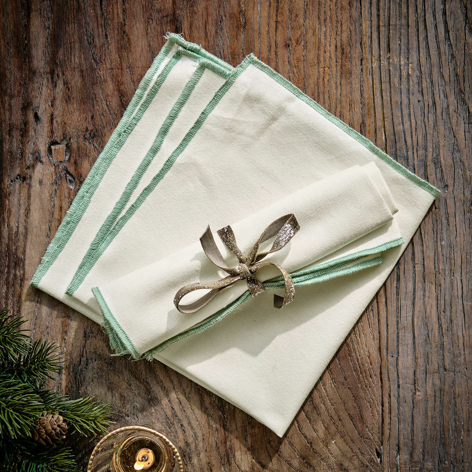 Servet set van 2 Tarivelle Set crèmekleurige linnen servetten met groene rand op houten tafel, kerstdecoratie