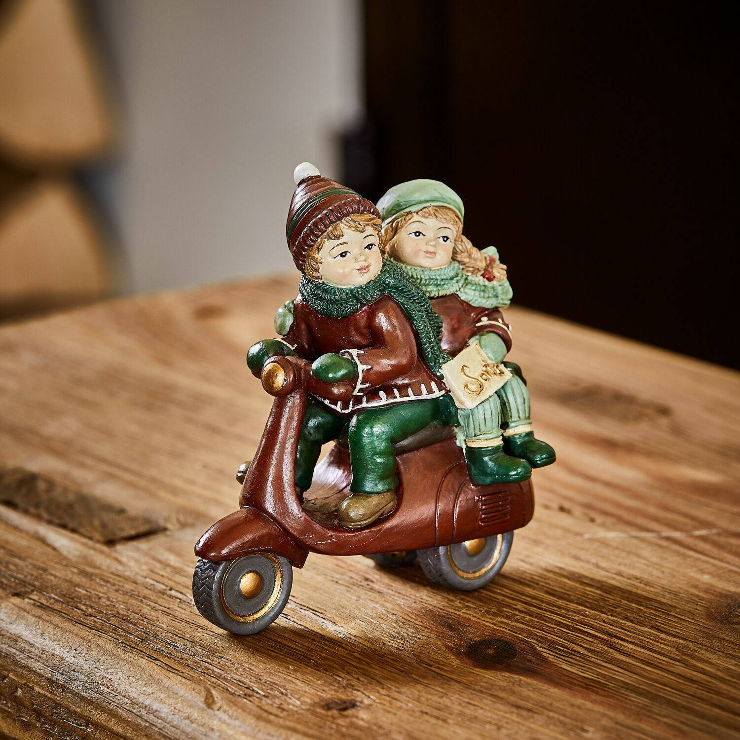 Beeldje Dariell Beeldje van kinderen op bruine scooter met groene kleding op houten tafel winterdecoratie