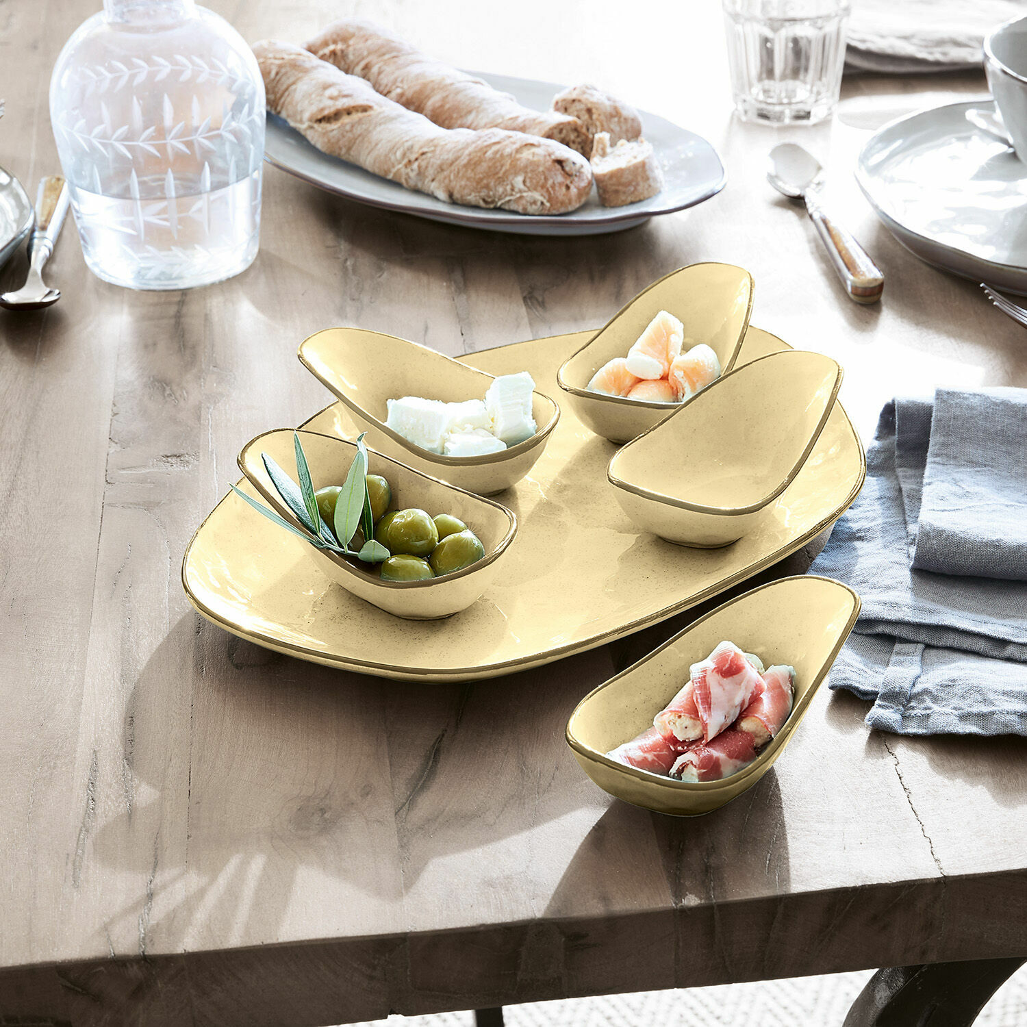 Set gele keramische schaaltjes voor snacks op houten tafel met olijven en kaas