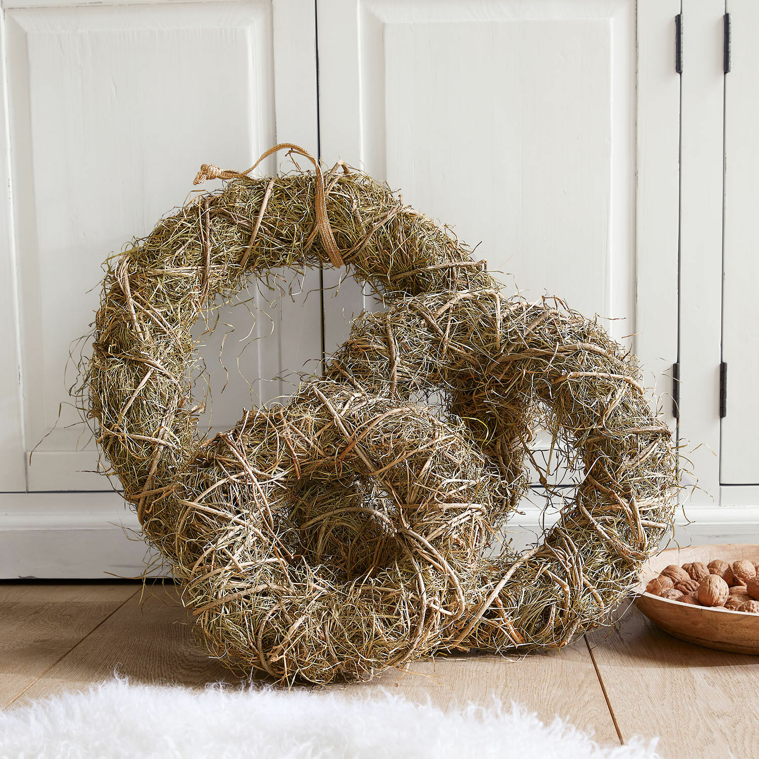 Sierkrans set van 3 Zahar Natuurlijke decoratieve krans van gras en takjes in bruin op de vloer bij een witte kast