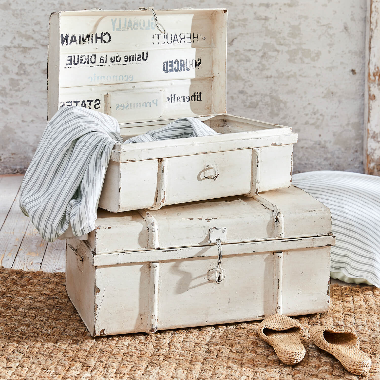 Witte houten kisten met verweerd effect op juten vloerkleed met gestreepte stof erin