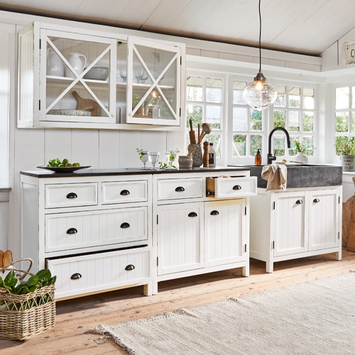 Witte houten keuken met lades, kasten, zwart werkblad en stenen gootsteen