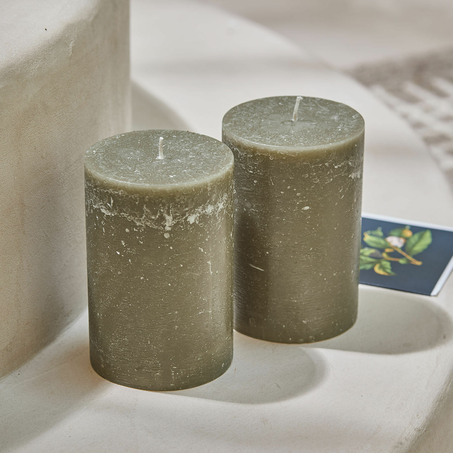 Twee groene kaarsen van was met rustieke textuur op een lichte ondergrond voor interieurdecoratie