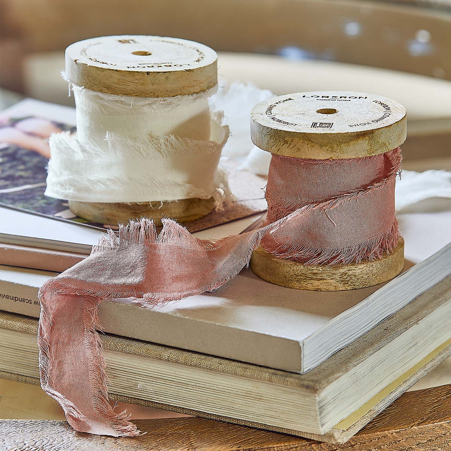 Houten spoelen met fijne witte en roze stof op een stapel boeken voor interieurdecoratie