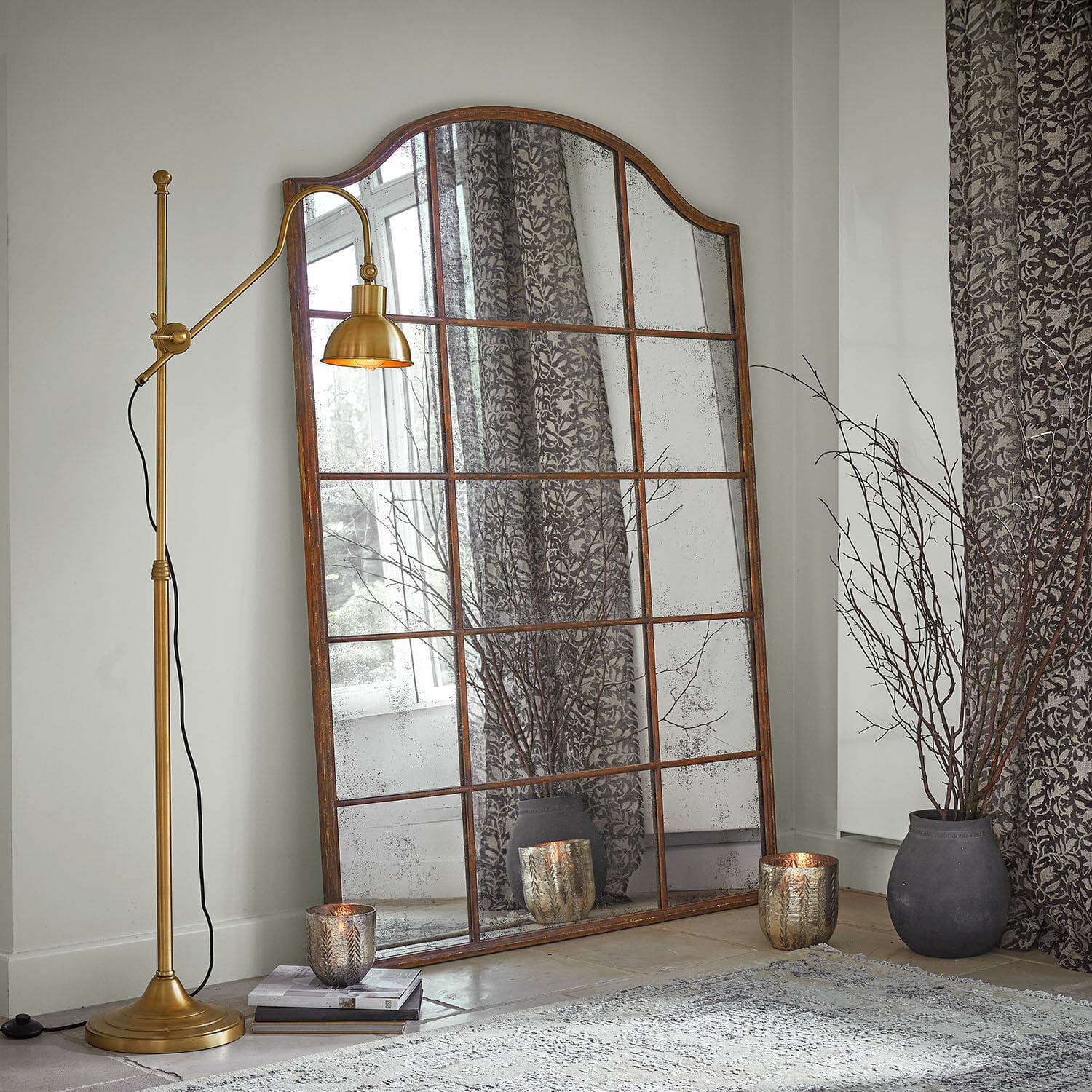 Spiegel Aimorie Grote spiegel met verweerde roestkleurige lijst, decoratieve kaarsen en gouden vloerlamp in woonkamer
