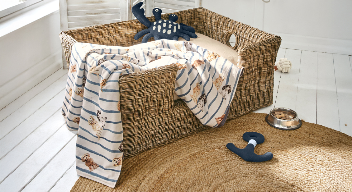 Rieten hondenmand met beige kussen en gestreept hondenprintdeken, maritieme speeltjes