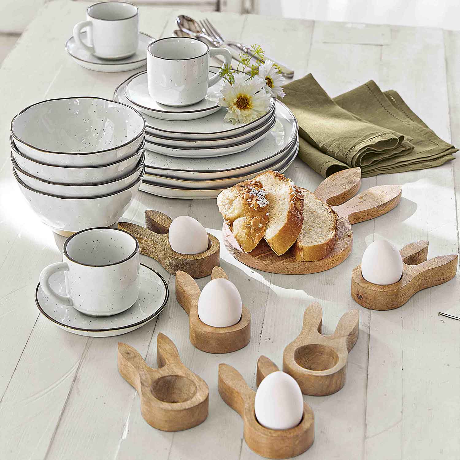 Witte keramische servies met bruine rand en houten eierhouders in konijnvorm voor het ontbijt