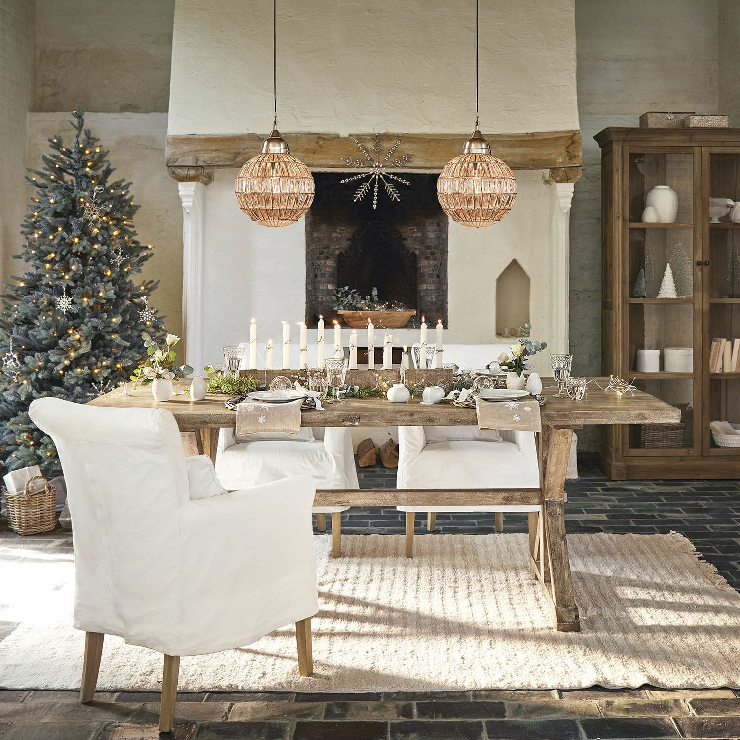 Eettafel Dolignon Rustieke houten tafel met witte stoelen en kerstdecoratie in een gezellige woonkamer met open haard
