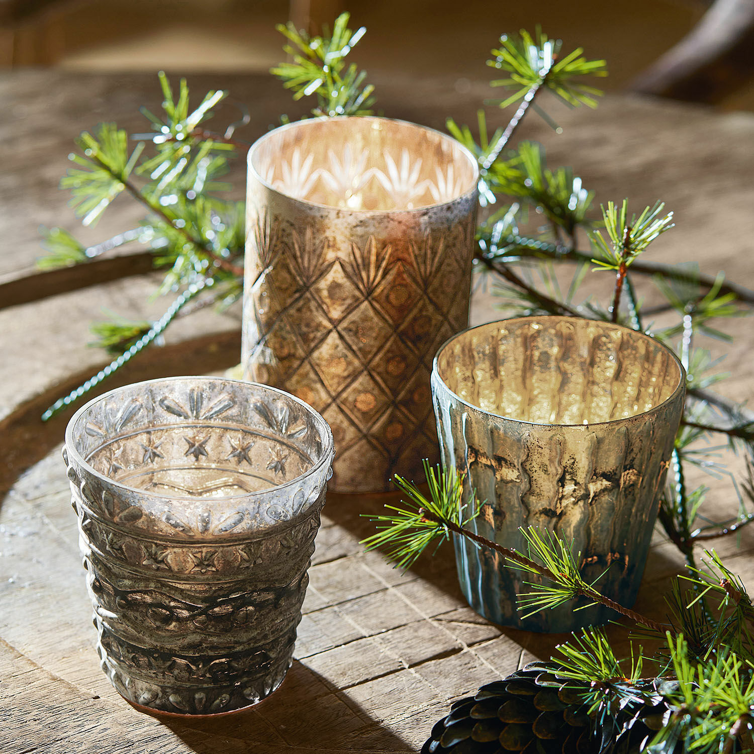 Set van drie glazen theelichthouders met decoratief patroon in bruin- en grijstinten op houten tafel