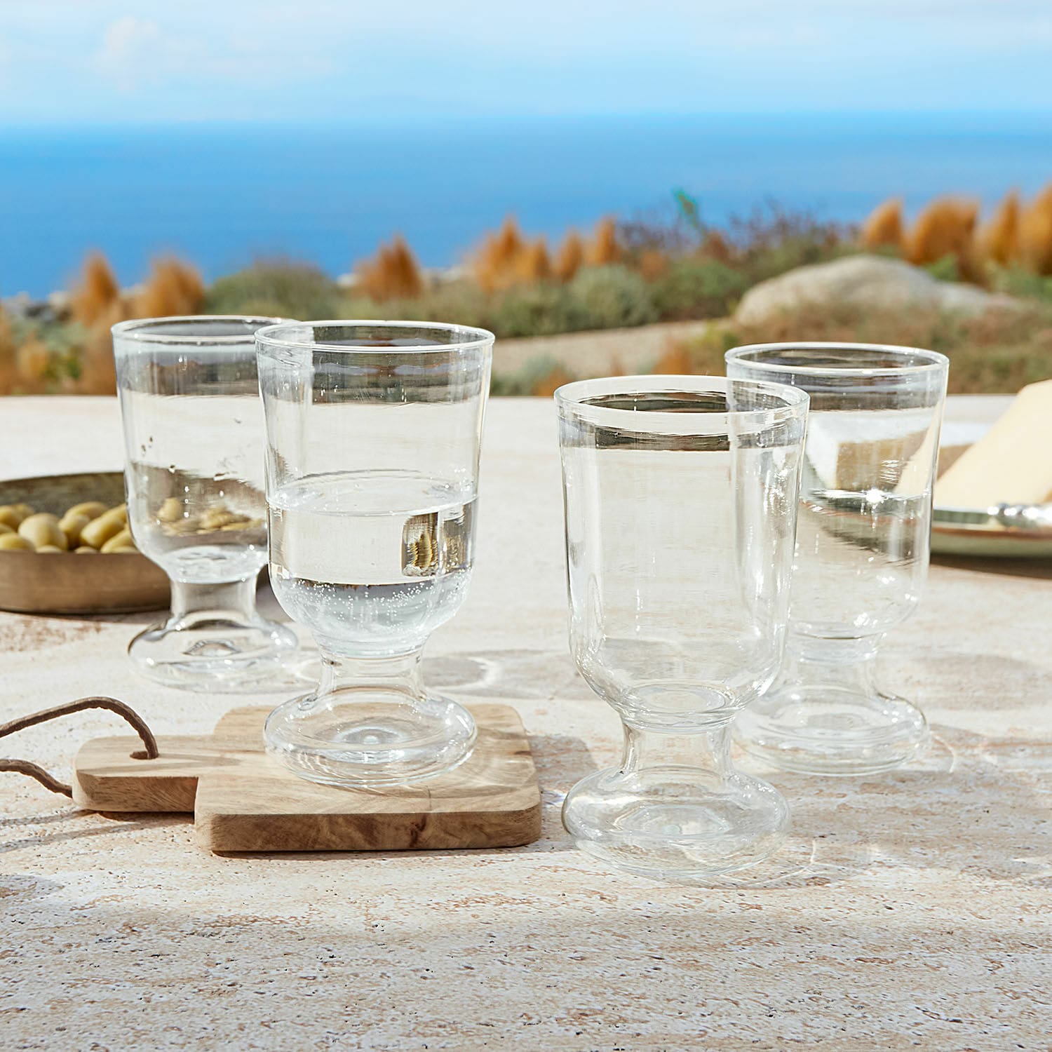 Glas set van 4 Yvoncourt Set van vier transparante glazen op voet op tafel met uitzicht op zee