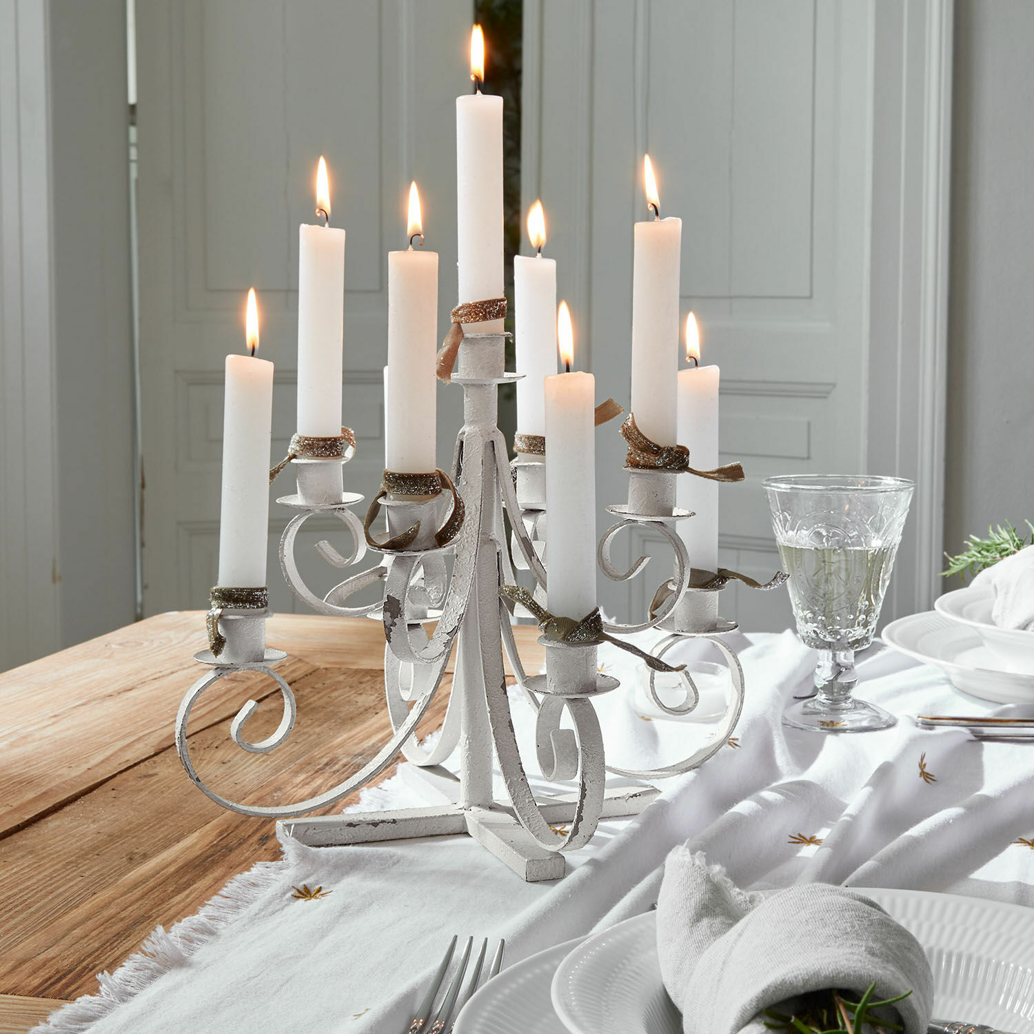 Kandelaar Siolagh Witte metalen kandelaar met negen brandende kaarsen op een houten tafel met tafeldecoratie