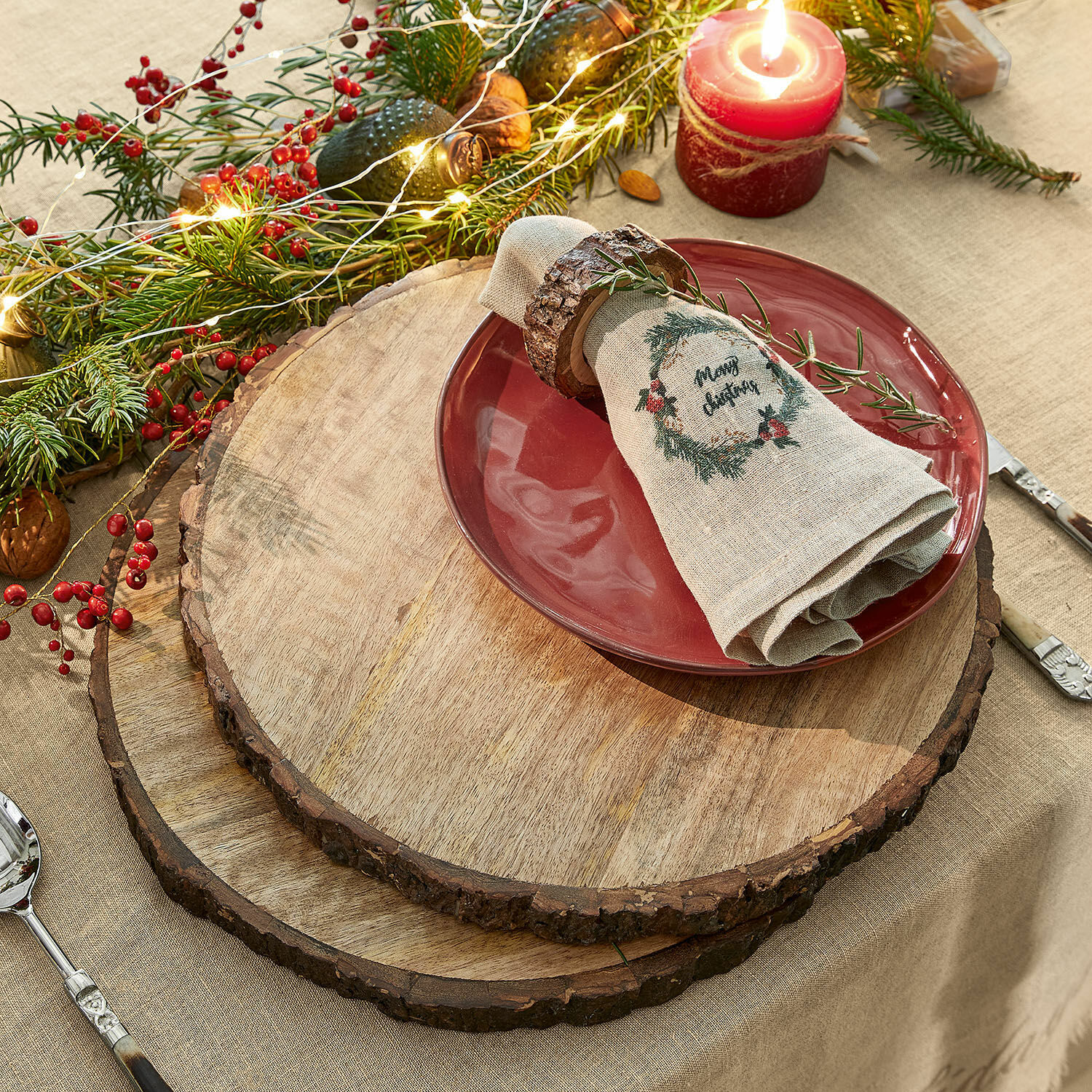Houten onderzetters met natuurlijke schors op feestelijk gedekte tafel met rood bord en kaars