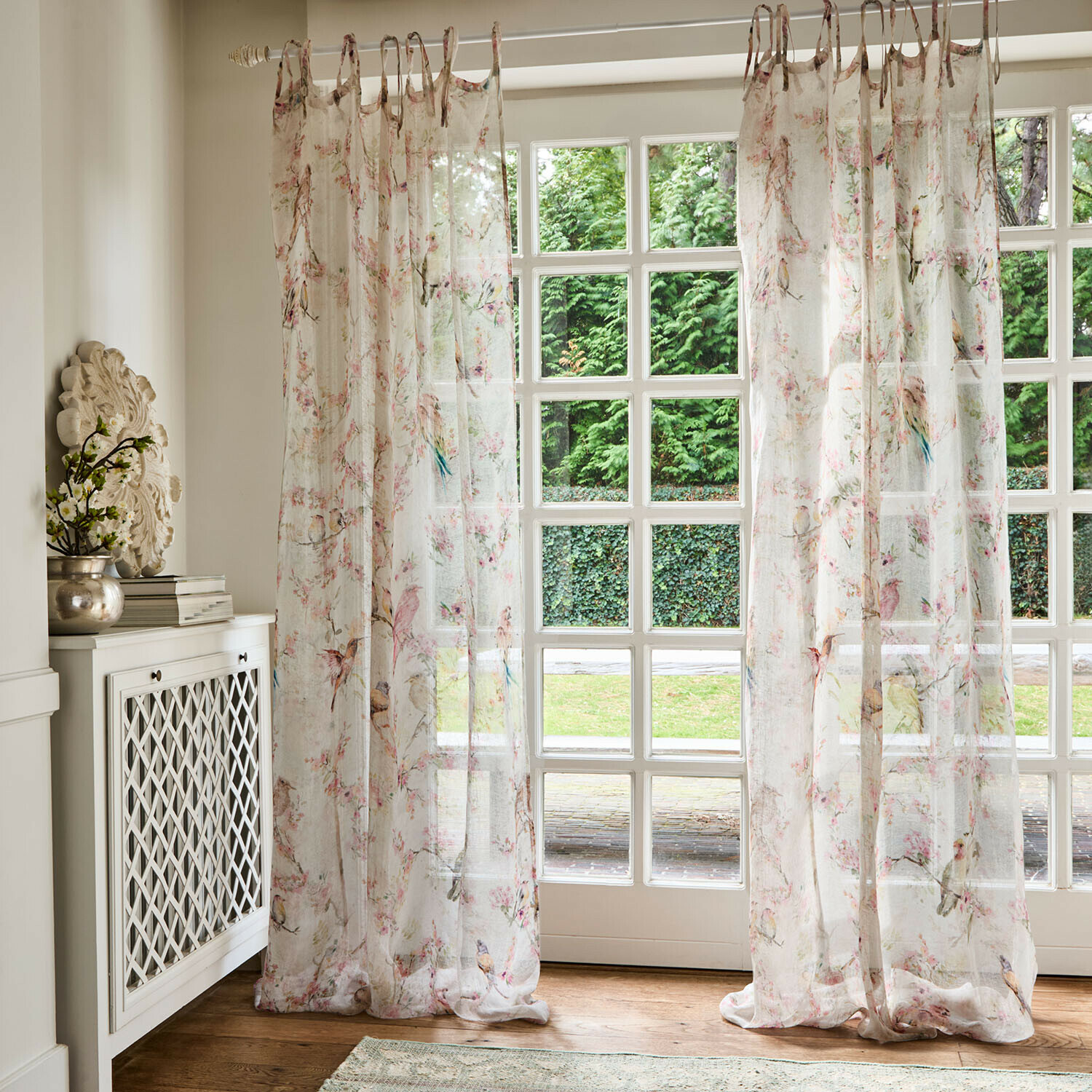 Transparante gordijnen met subtiel bloemen- en vogelpatroon in lichte pasteltinten voor een lichte sfeer