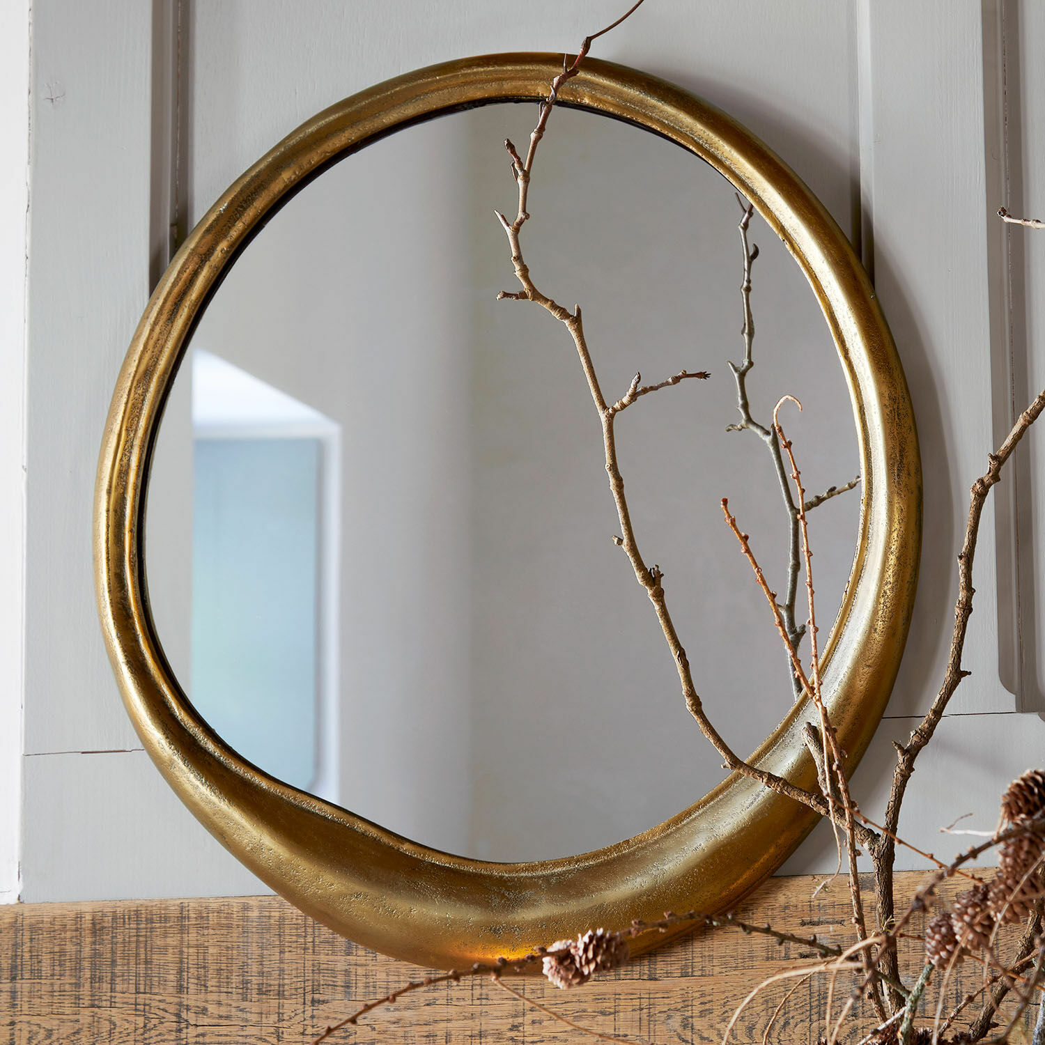 Spiegel Caloréa Ronde spiegel met antiek gouden lijst aan houten wand, versierd met droge takken