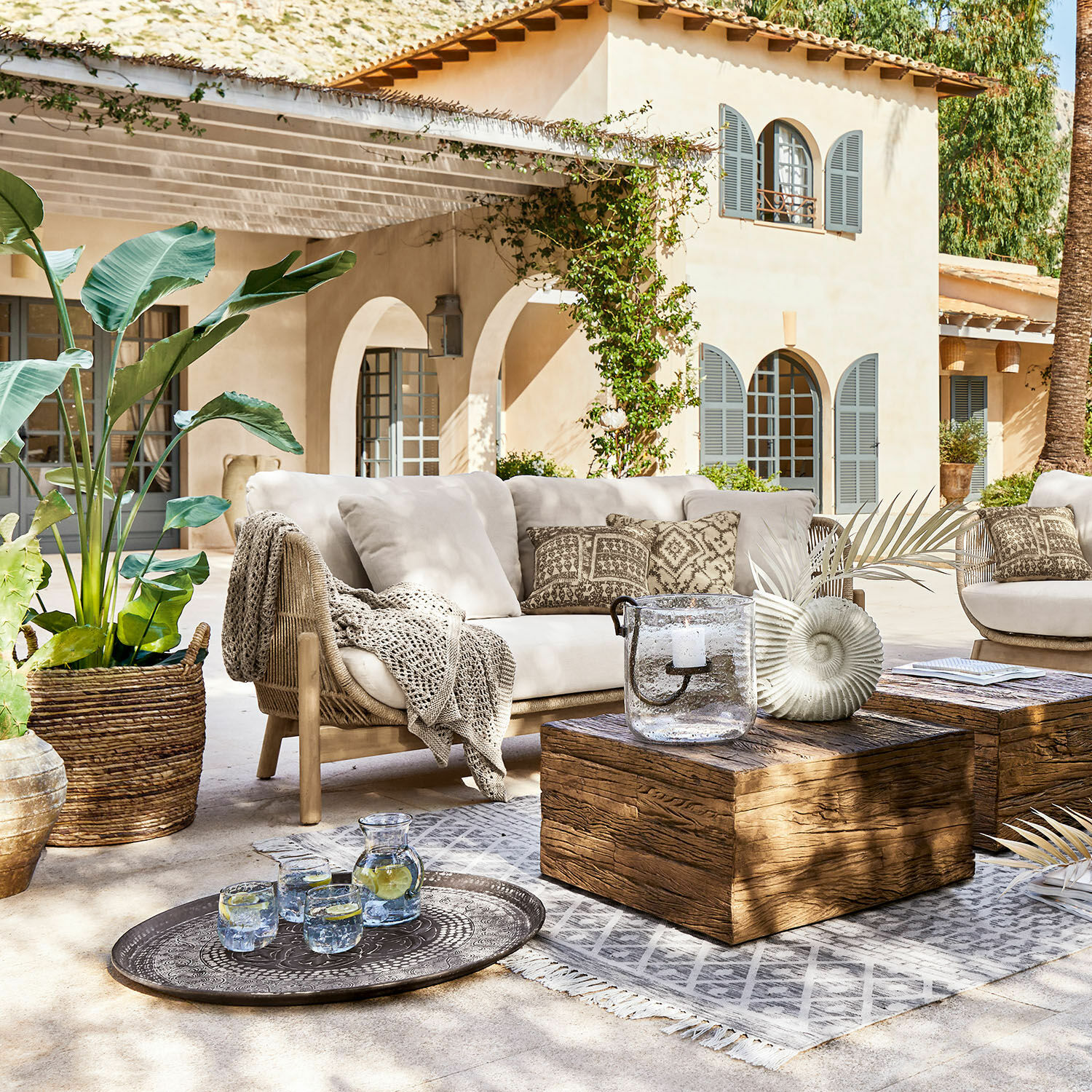 Bank FSC®-100% Belvidere Buitenmeubelset met beige bank, houten tafel en decoraties op zonnig terras