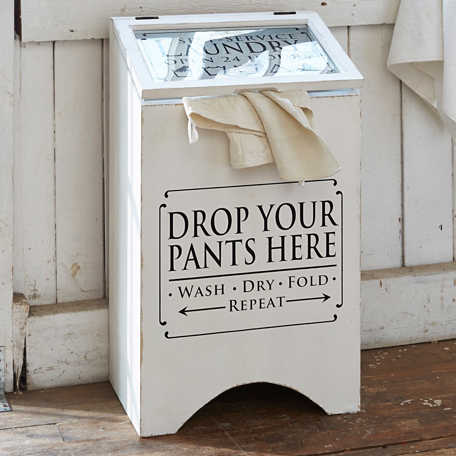 Wasbox Drop it Witte houten wasmand met tekst en crème handdoek op houten vloer