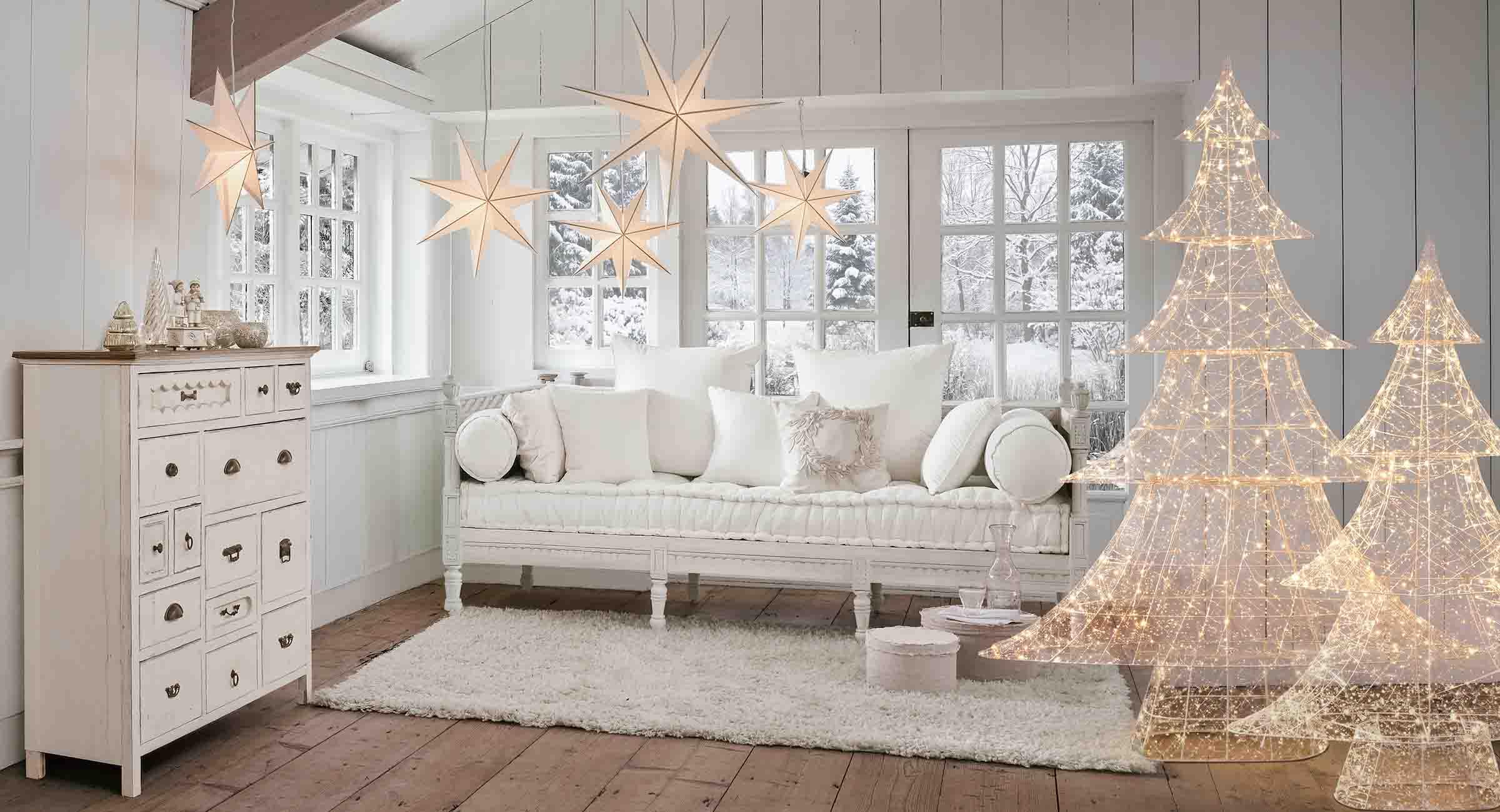 Gezellige witte woonkamer met verlichte ster- en boomdecoraties voor de winter