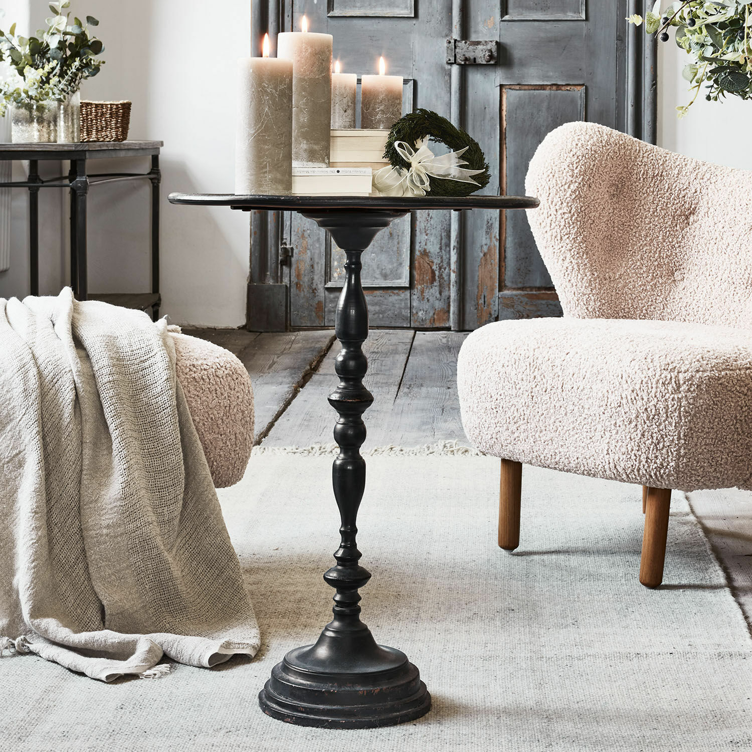 Zwarte metalen bijzettafel met decoratieve vintage voet in gezellige woonkamer