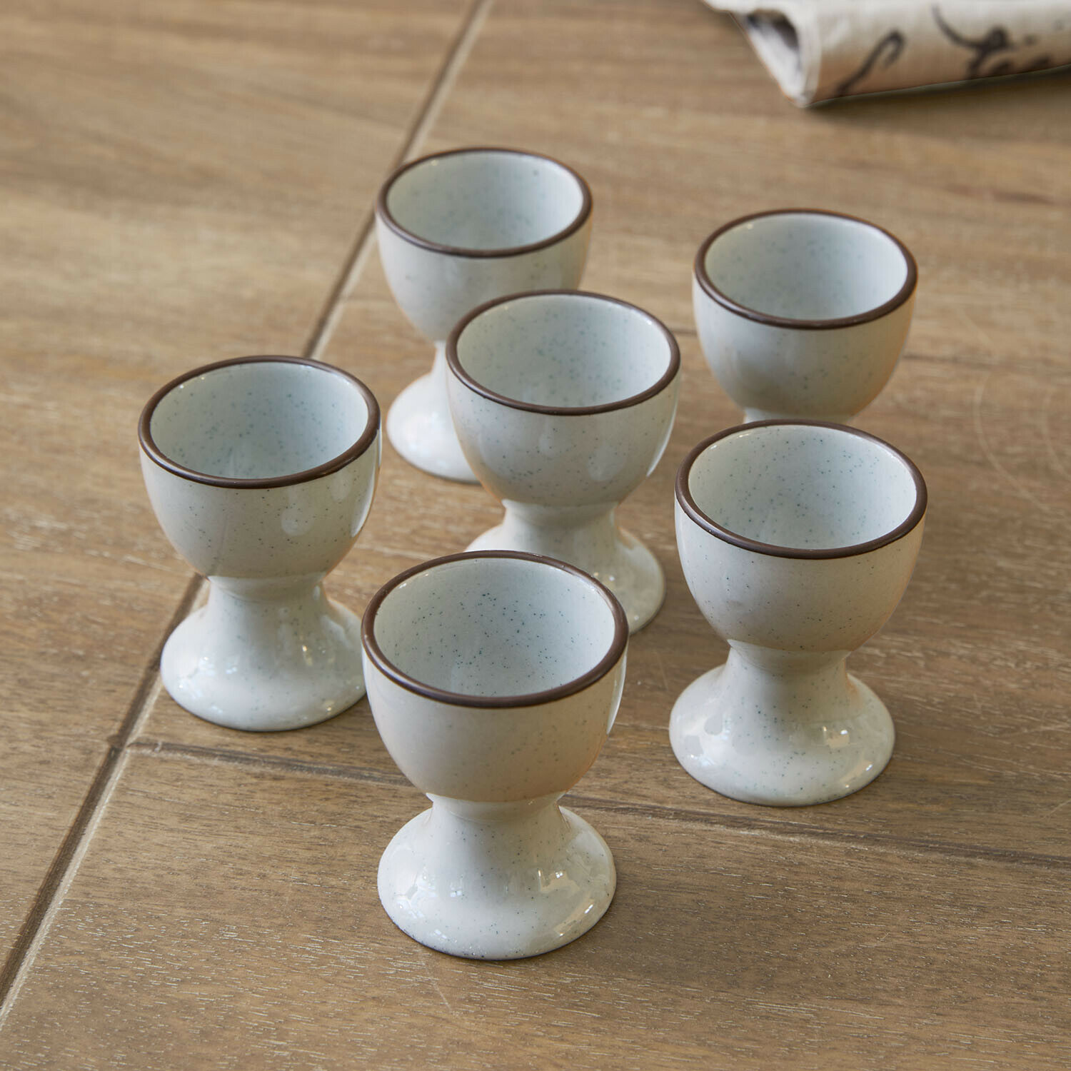 Eierdopje set van 6 Biarré Set van zes crèmekleurige keramische eierdopjes met bruine rand op houten tafel