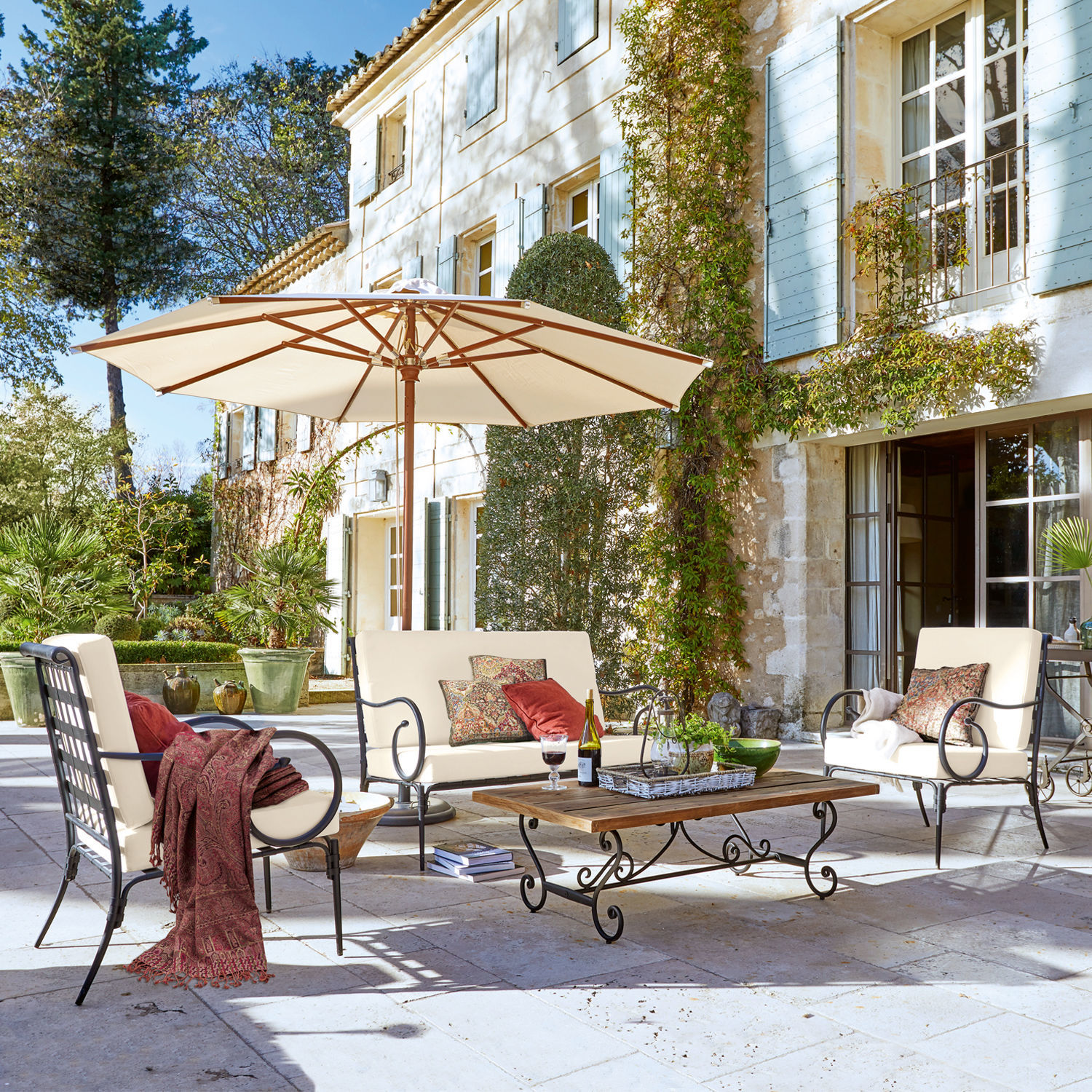 Tuinset Massana Tuinmeubelset met metalen frame en crèmekleurige kussens op stenen terras met parasol