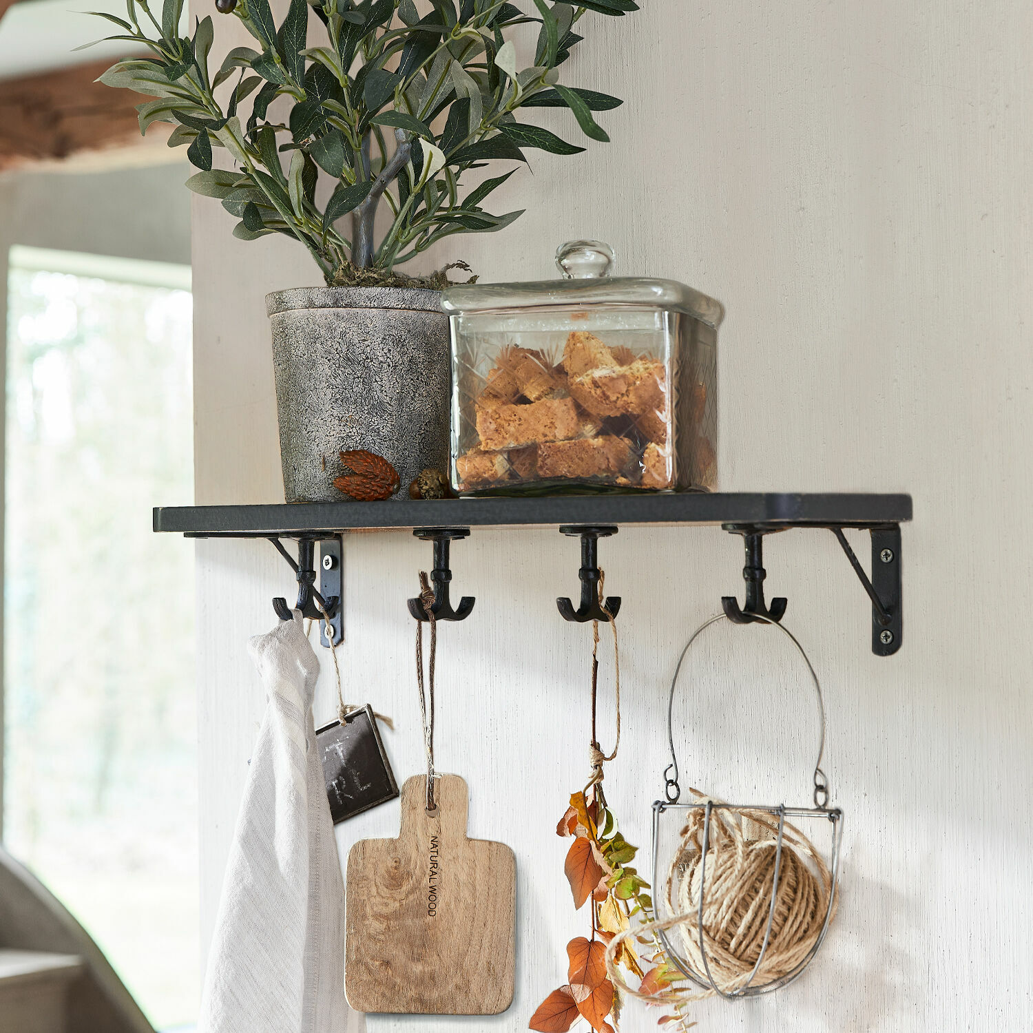 Wandplank Agnessa Zwart metalen wandplank met haken, bloempot en glazen pot met koekjes erop
