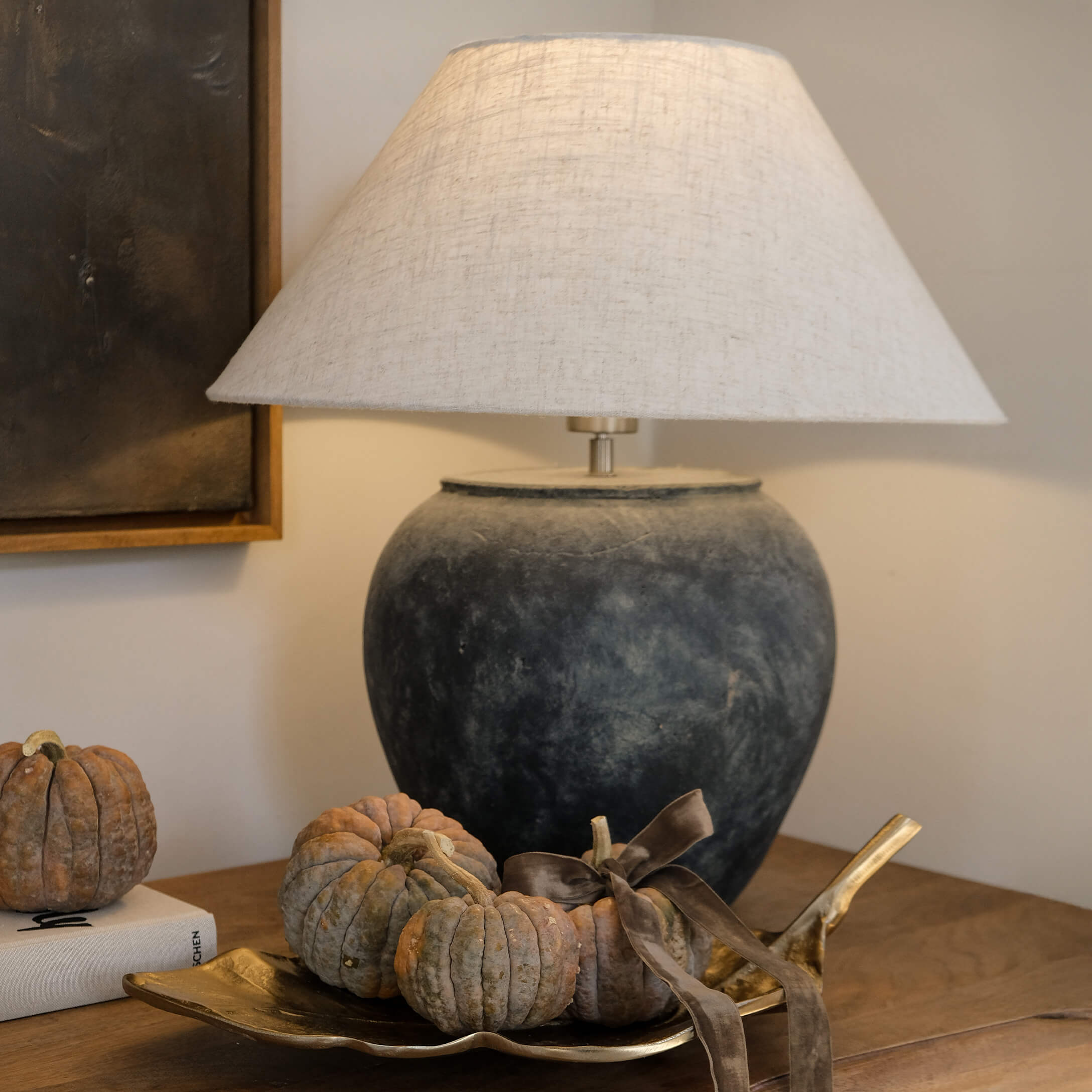 Tafellamp van donkergrijs keramiek met beige kap en decoratie van kleine pompoenen op gouden schaal