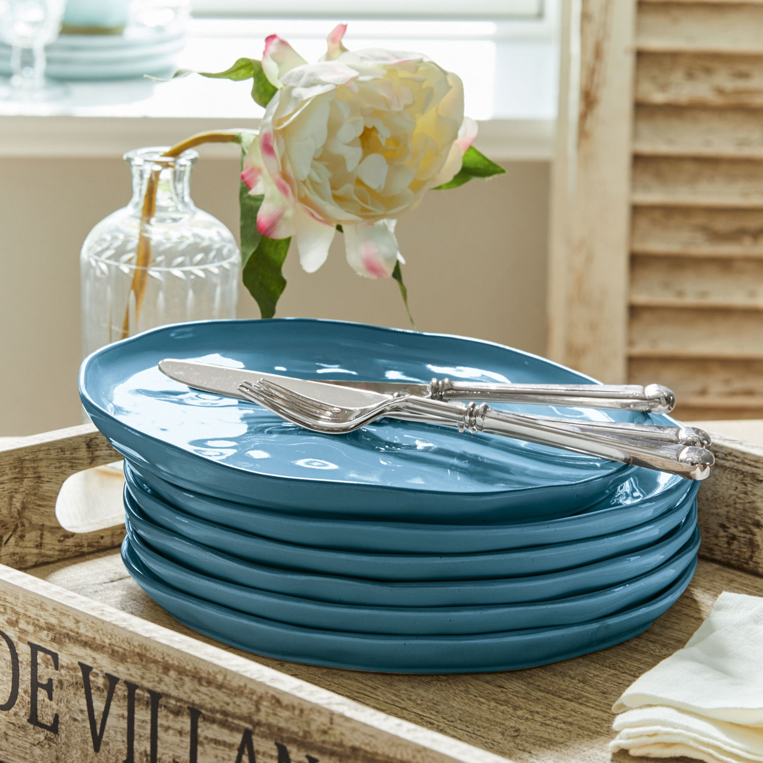 Set blauwe keramische borden op houten dienblad met mes en vork, tafeldecoratie